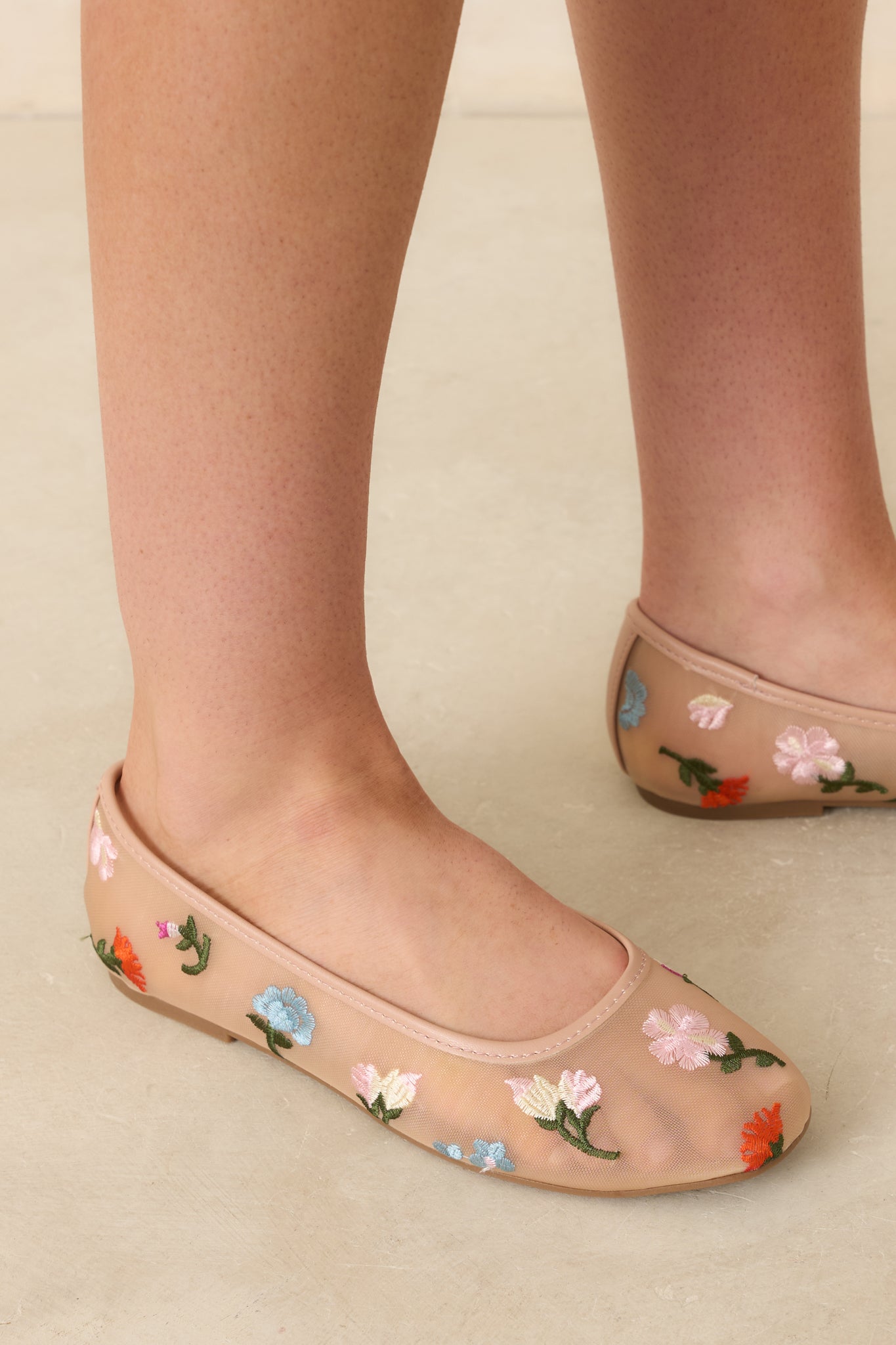 Close-up of nude mesh flats featuring intricate floral embroidery and lightweight, sheer texture