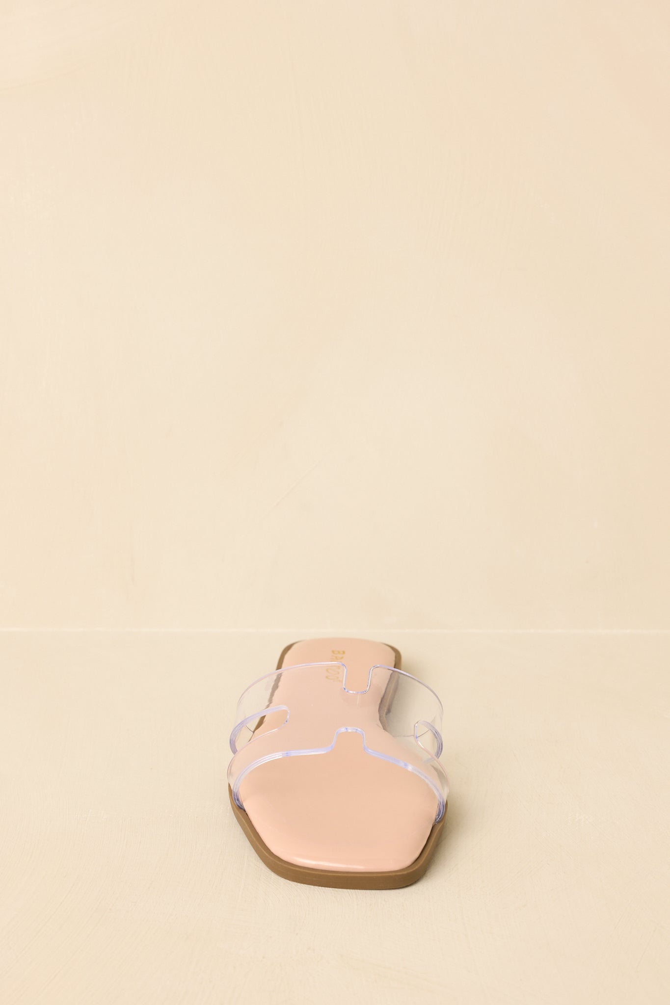 Front view of nude slide sandals displaying open square toe and wide clear strap.