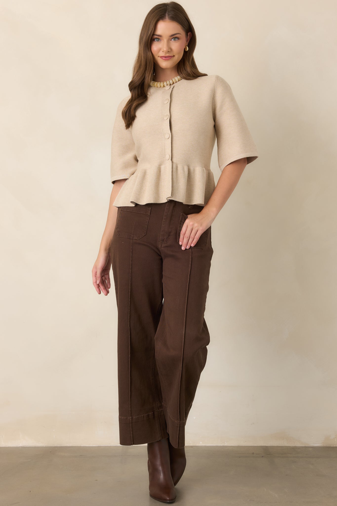 Oatmeal viscose-blend knit top featuring a round neckline, fabric-covered buttons, elbow-length sleeves, fitted bodice, and softly gathered peplum hem.