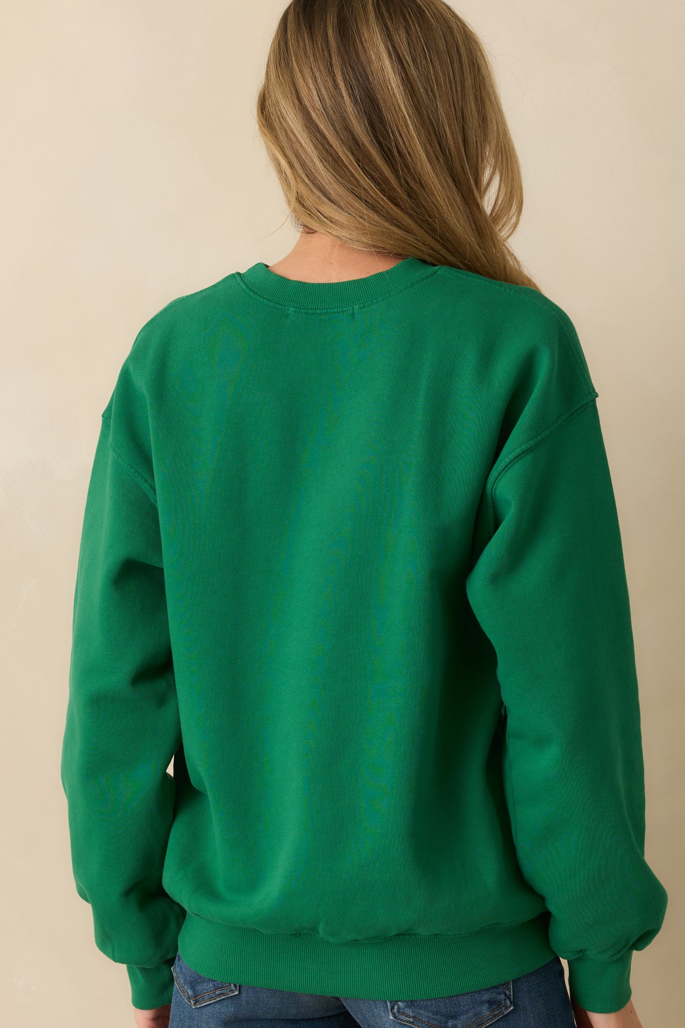 Rear view of the green sweatshirt displaying a plain design with ribbed trim along the hem and cuffs.