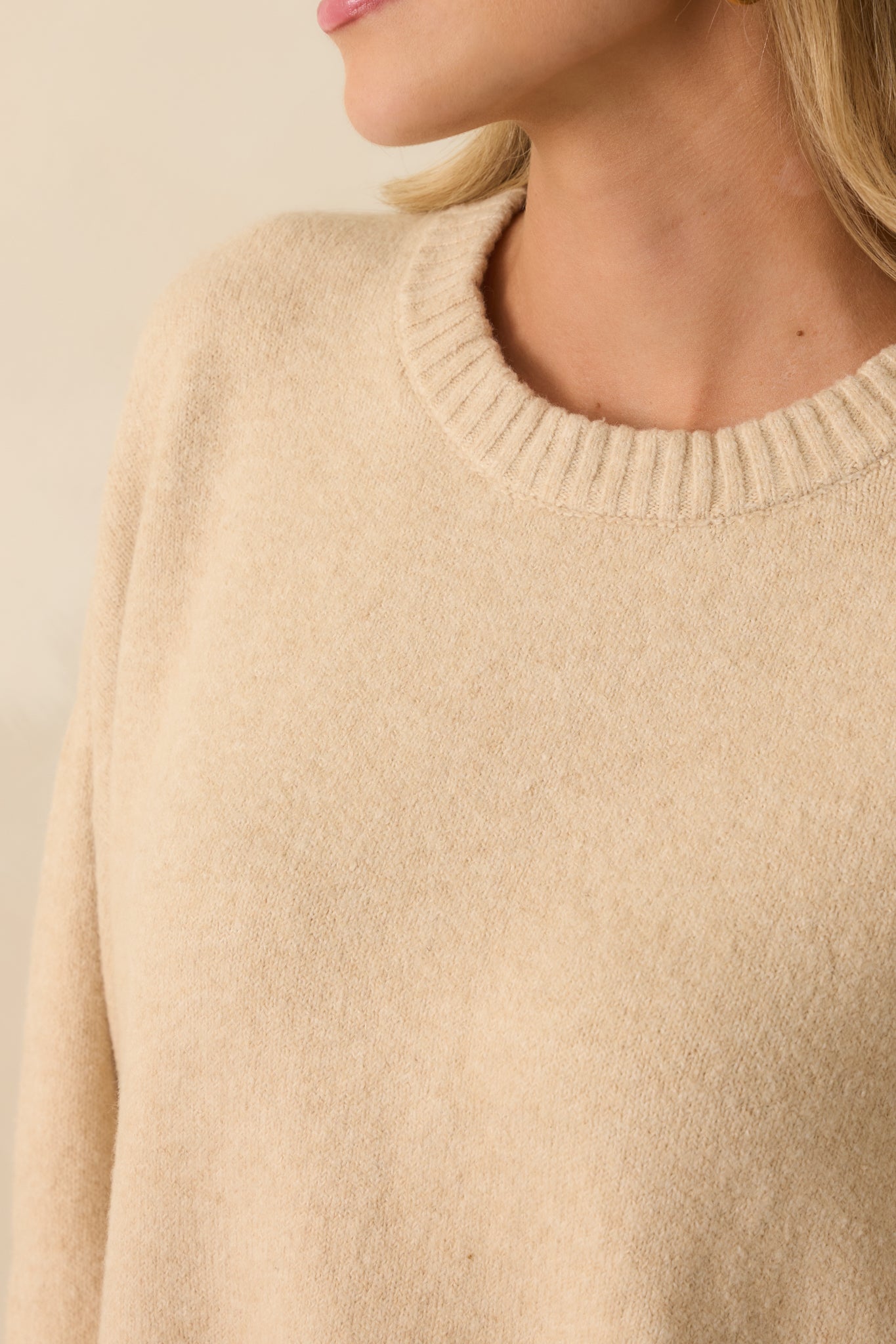 Close-up detail of the knit texture, ribbed neckline, and sleeve hem.