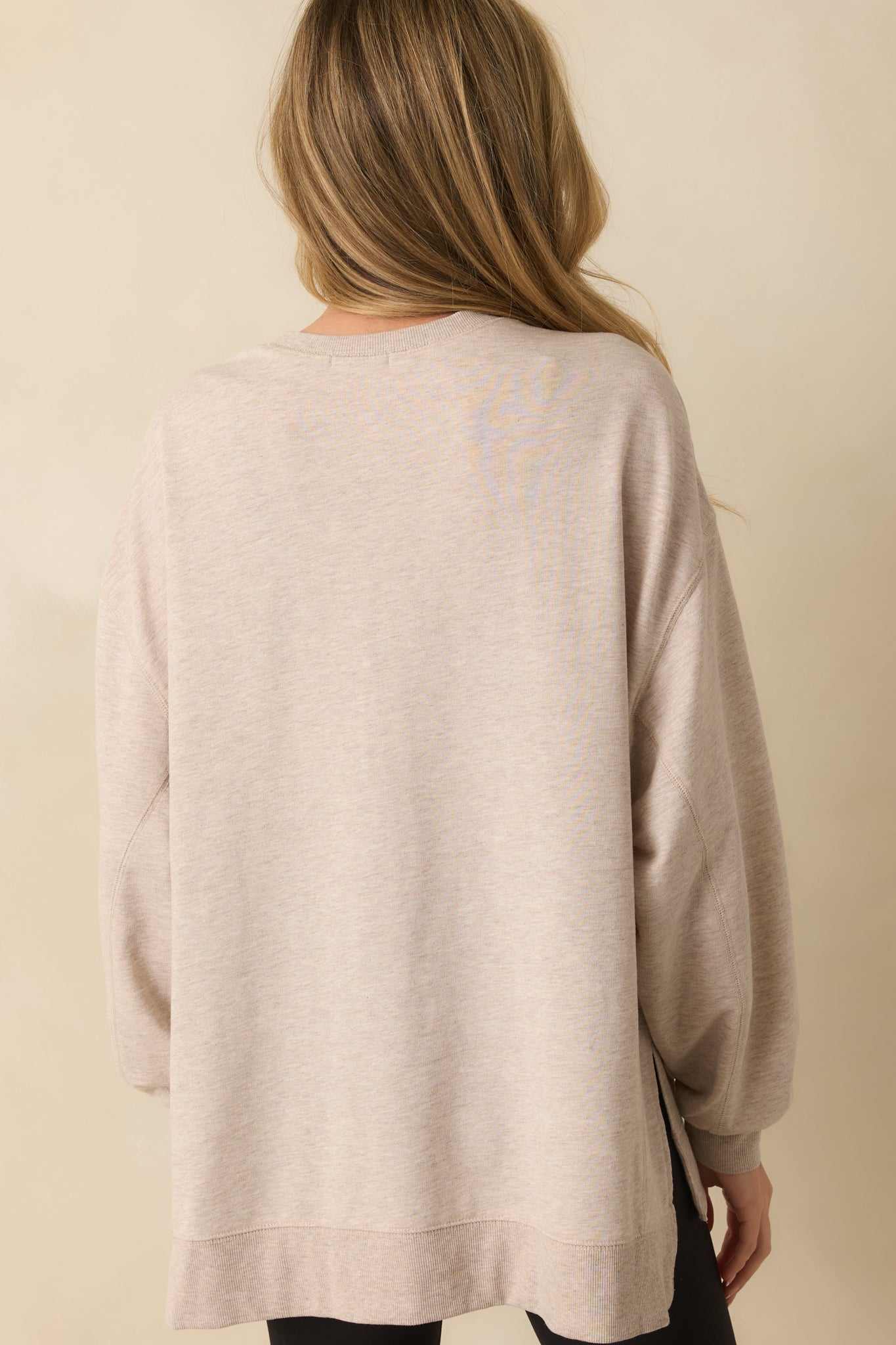 Rear view of the sweatshirt showing the relaxed fit, long sleeves, and high-low hemline with side slits.