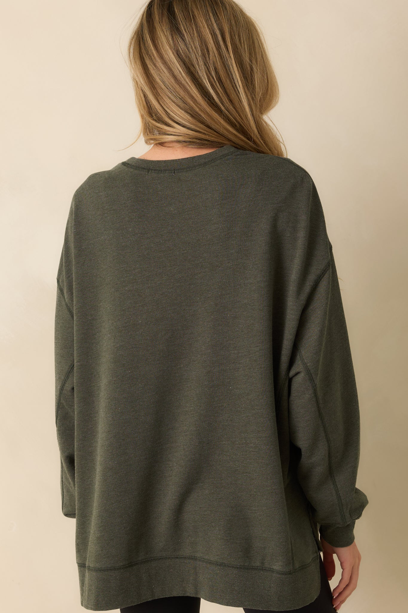 Back view of the sage green sweatshirt showing the relaxed drape and curved high-low hem.