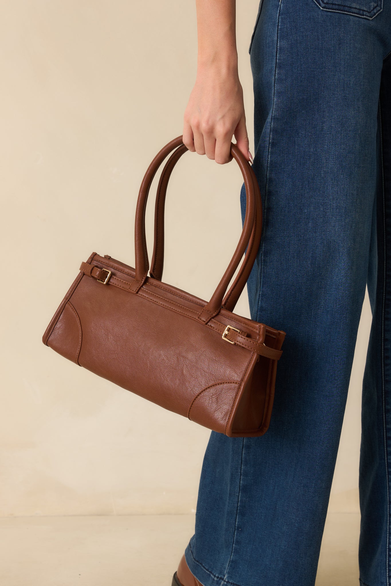 View showcasing the rich cognac hue and smooth faux leather texture of the handbag with subtle gold details.