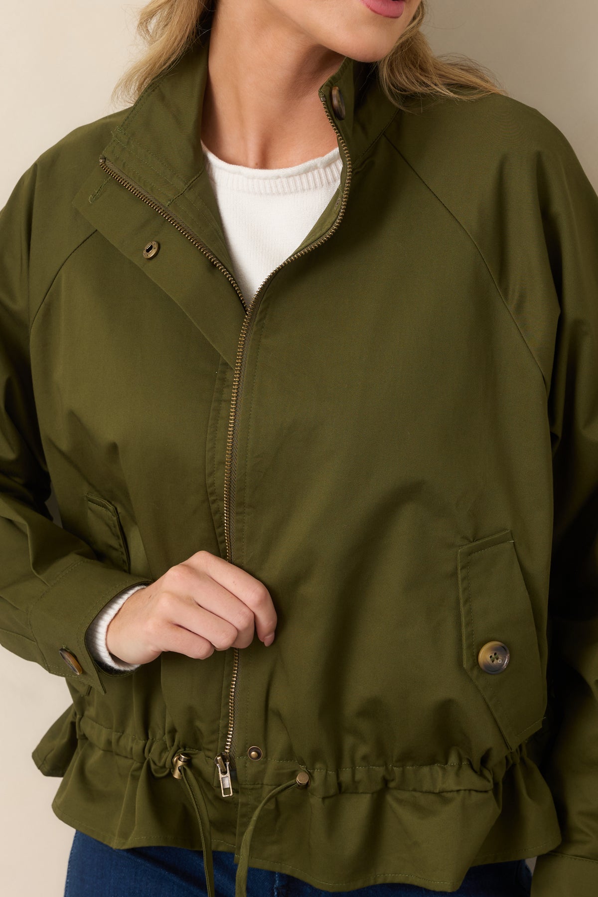 Close view of the olive cotton fabric, snap accents, zip closure, and pocket detailing.