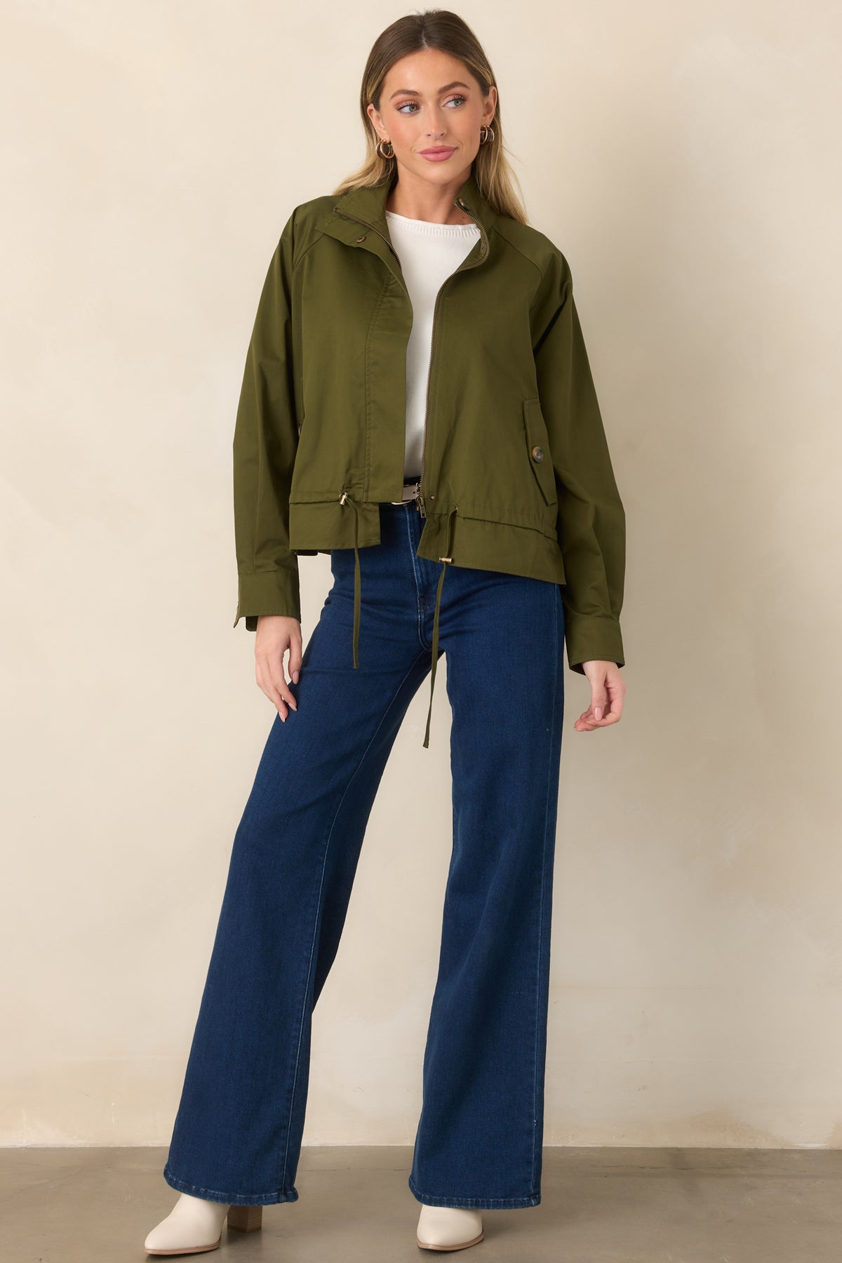 Olive cotton utility jacket defined by a structured stand collar and adjustable gathered waist.