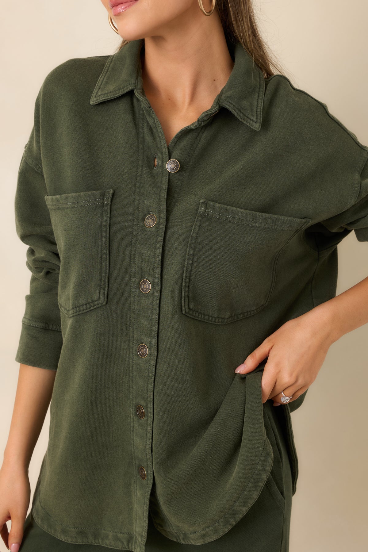 Close-up of the washed olive French terry jacket’s fabric texture and button-front detail.