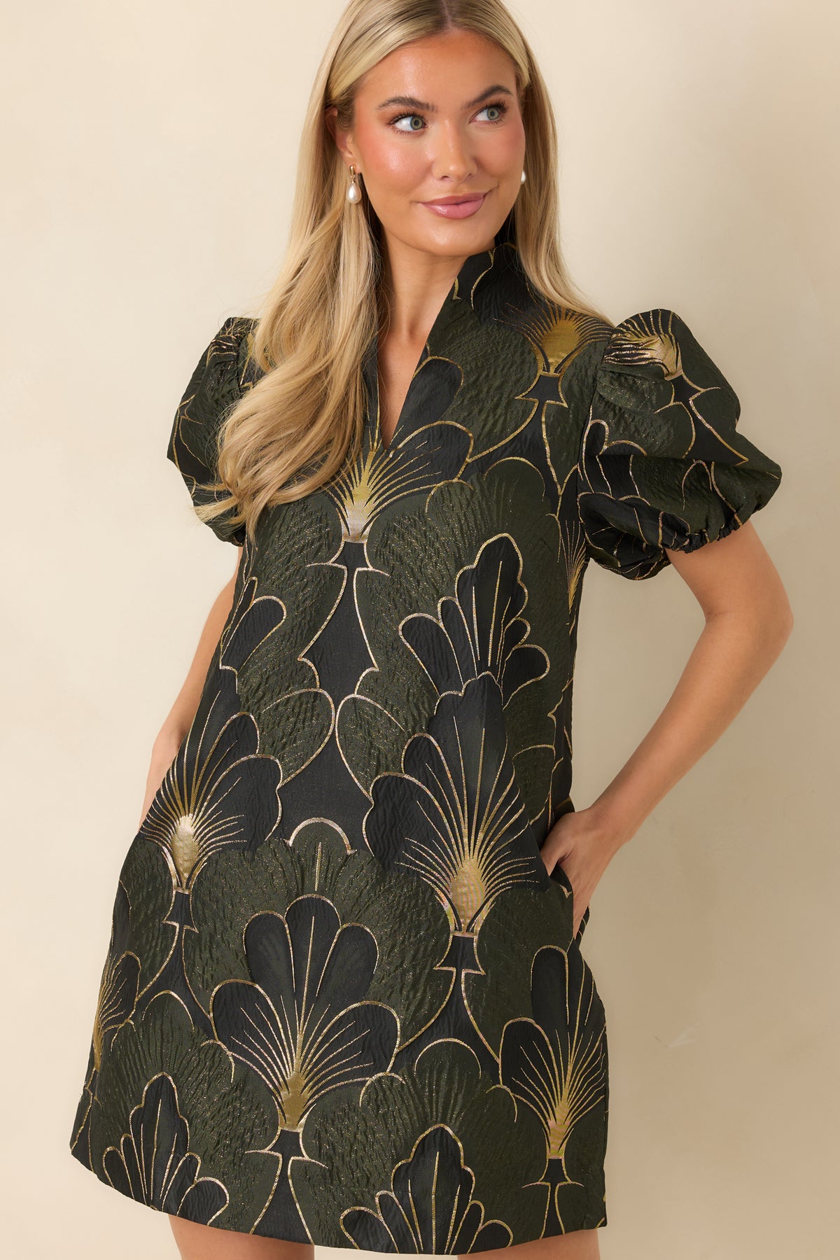 Oversized fan-shaped florals in olive, black, and shimmering gold cover the textured dress fabric.