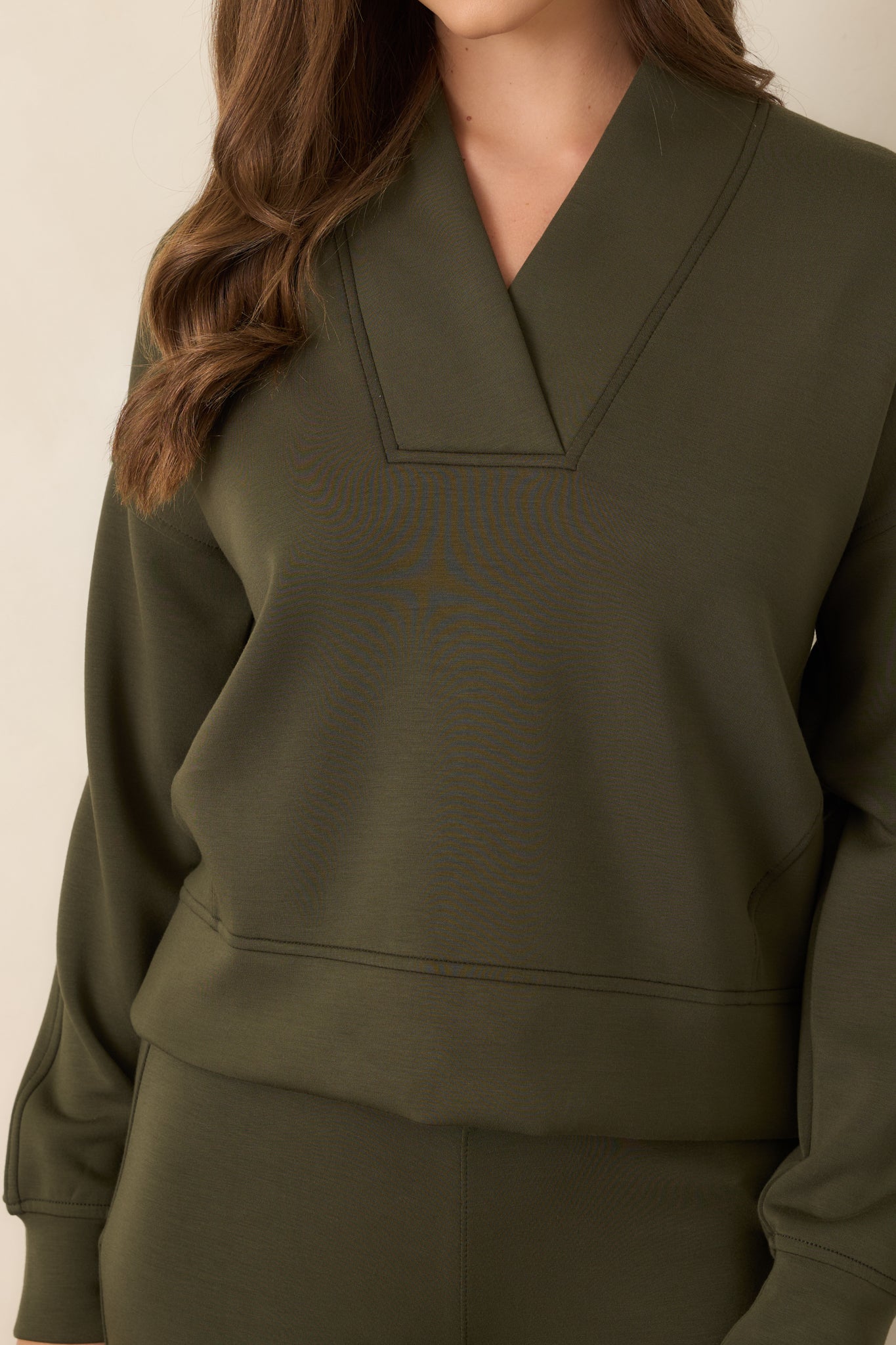 Detailed view of the olive-green top highlighting the smooth AirEssentials® fabric and precise seamed finish.