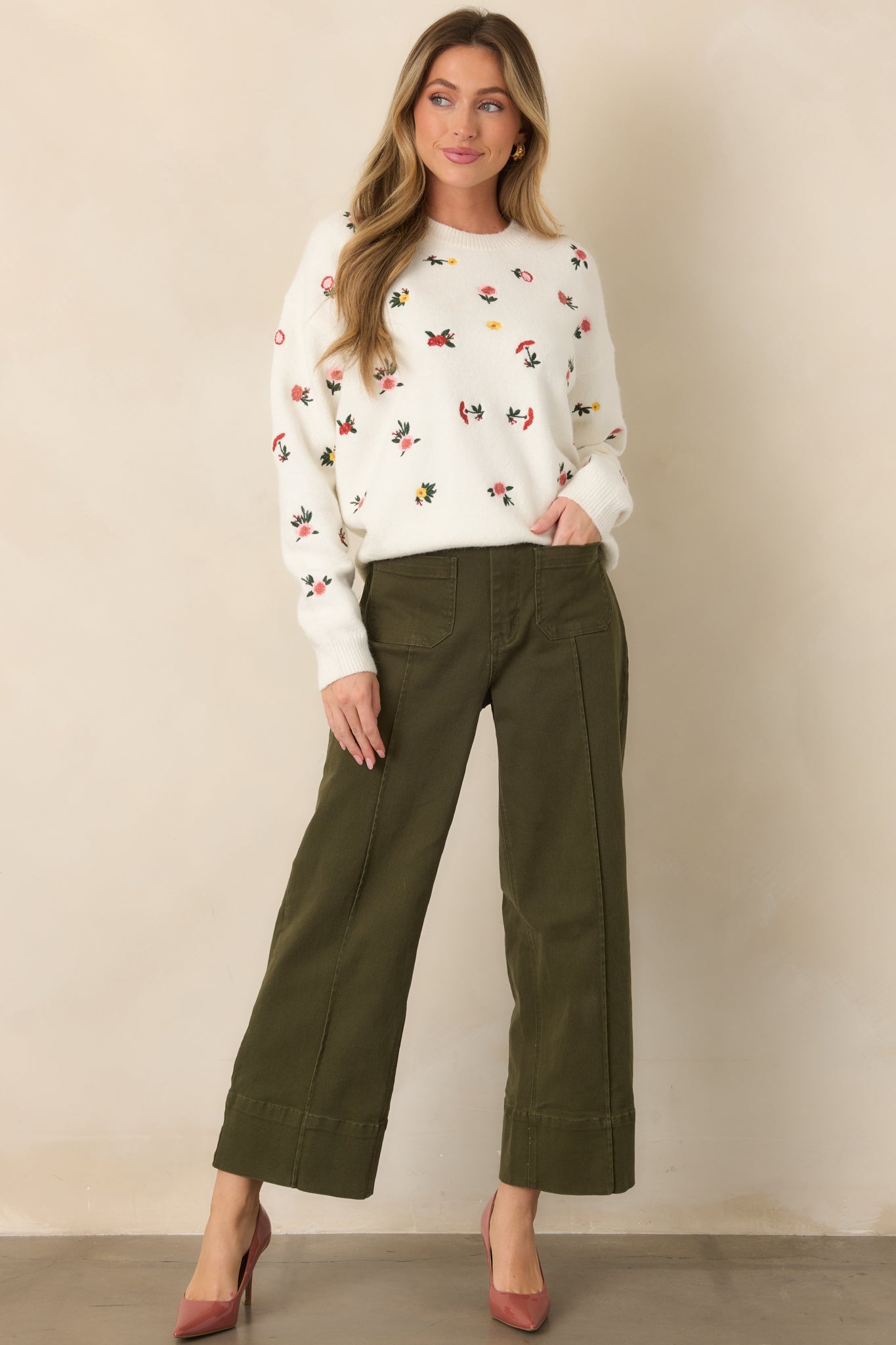 Olive green pants featuring a high-rise waist, cropped wide-leg silhouette, pressed center seams, and oversized front patch pockets.