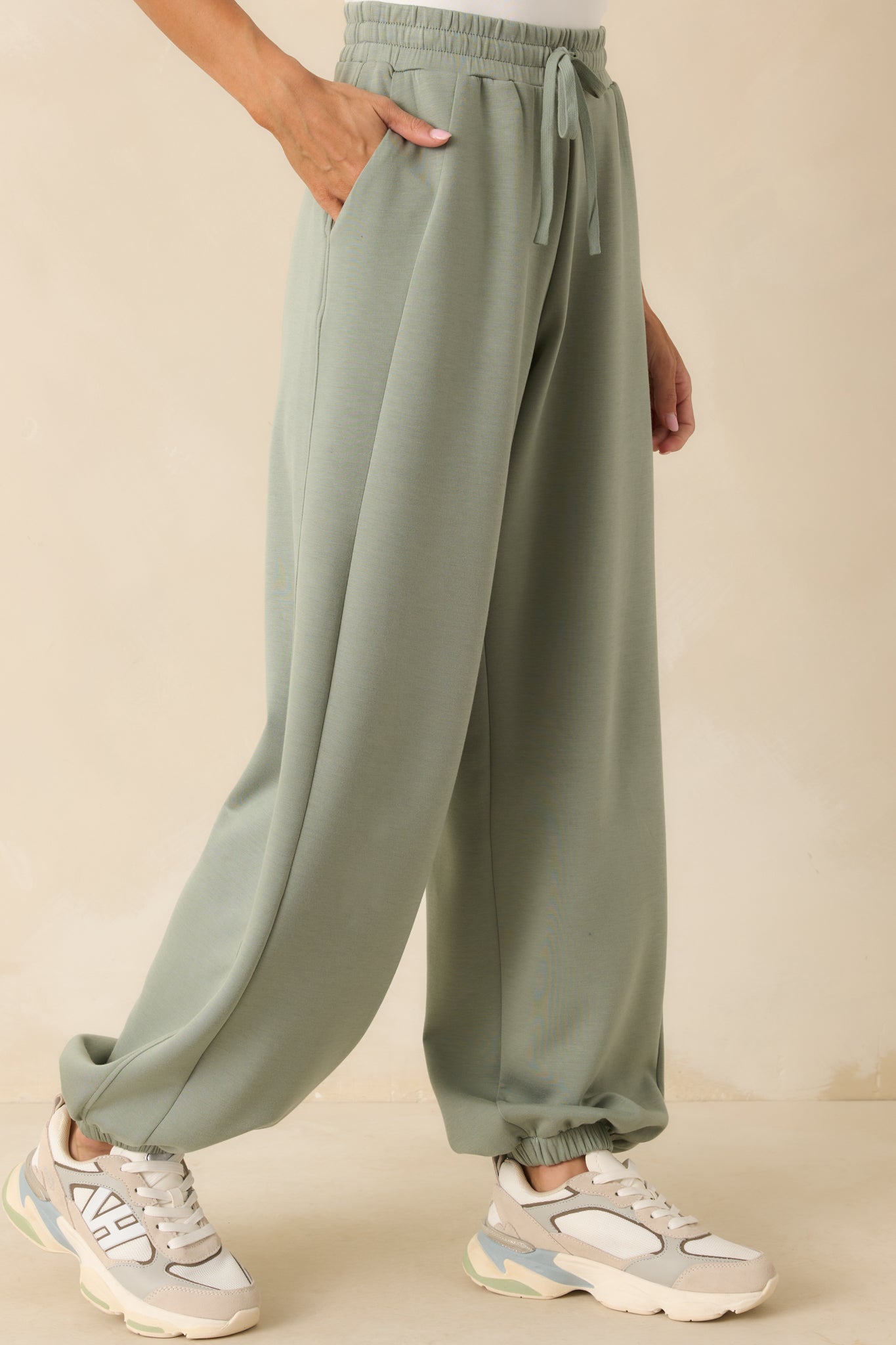 Cropped shot focusing on one hip pocket and the smooth olive green fabric.