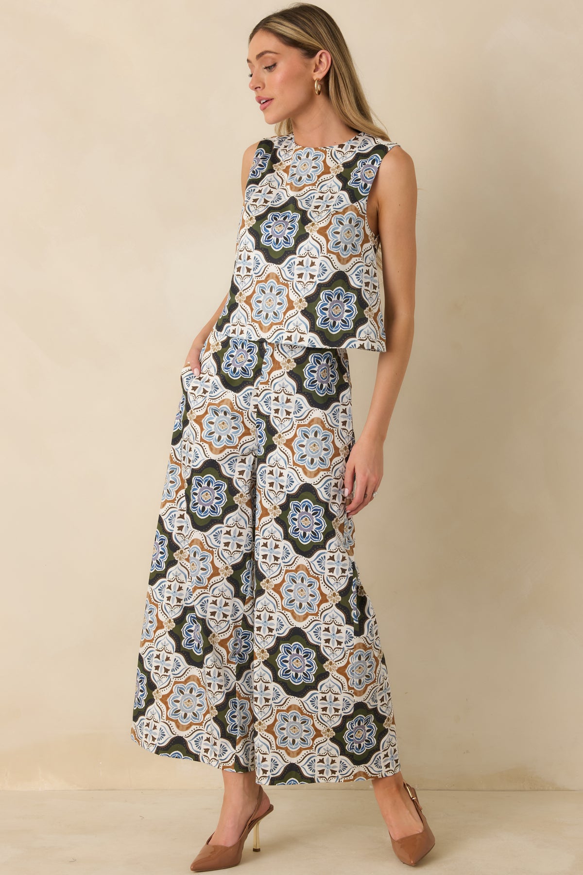 Olive green printed pants featuring an ornate multicolor medallion pattern, high-rise waist, and wide-leg silhouette.