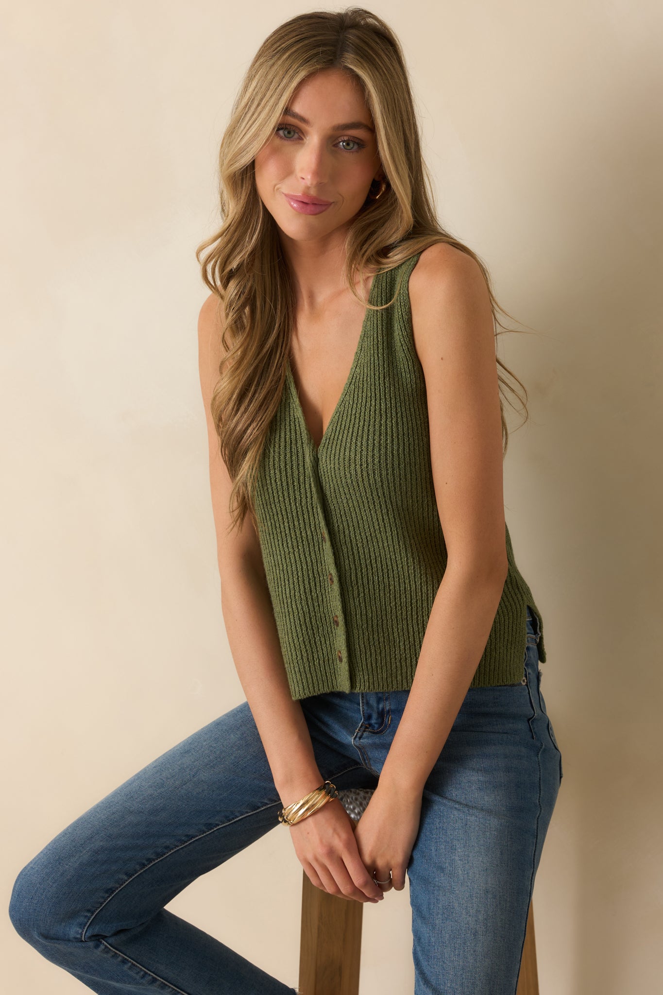 Olive green sleeveless vest with v-neckline and button front, styled in a clean and relaxed silhouette.