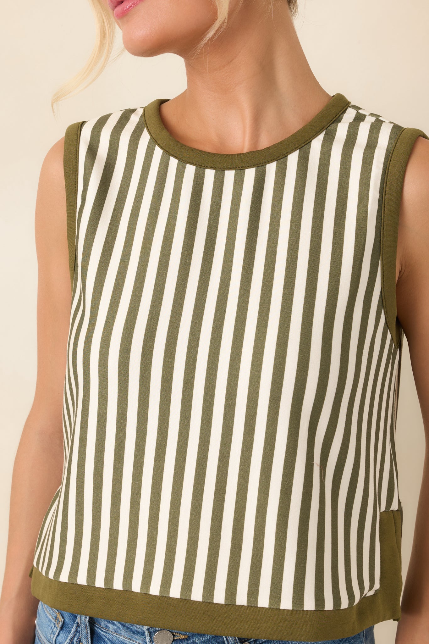 Close-up of the olive contrast trim and vertical striped fabric, highlighting the top’s neat round neckline and polished finish.