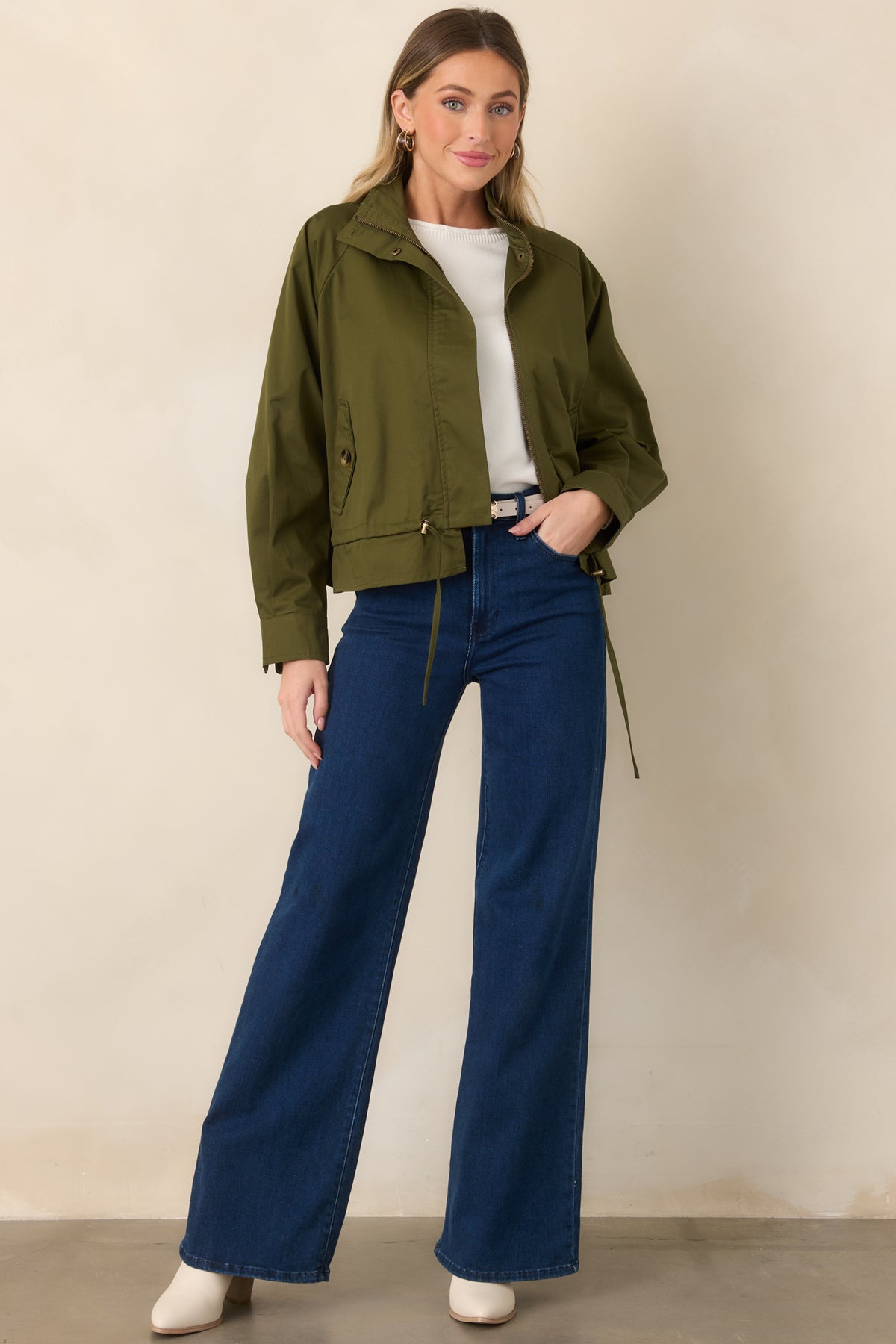 Lined olive utility jacket featuring functional flap pockets and an adjustable drawstring waist.