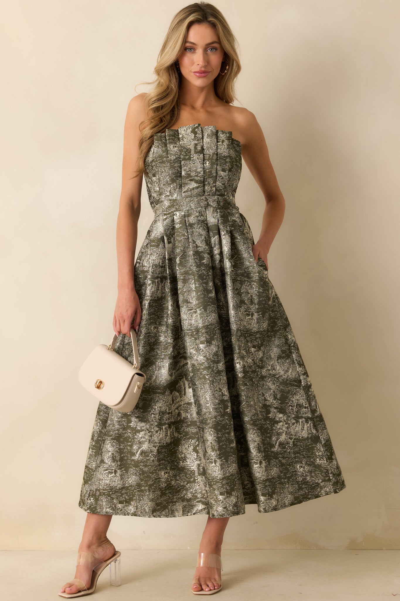 Olive strapless midi dress with an ivory jacquard pattern featuring castle and unicorn motifs, pleated structured bodice, and voluminous A-line skirt.