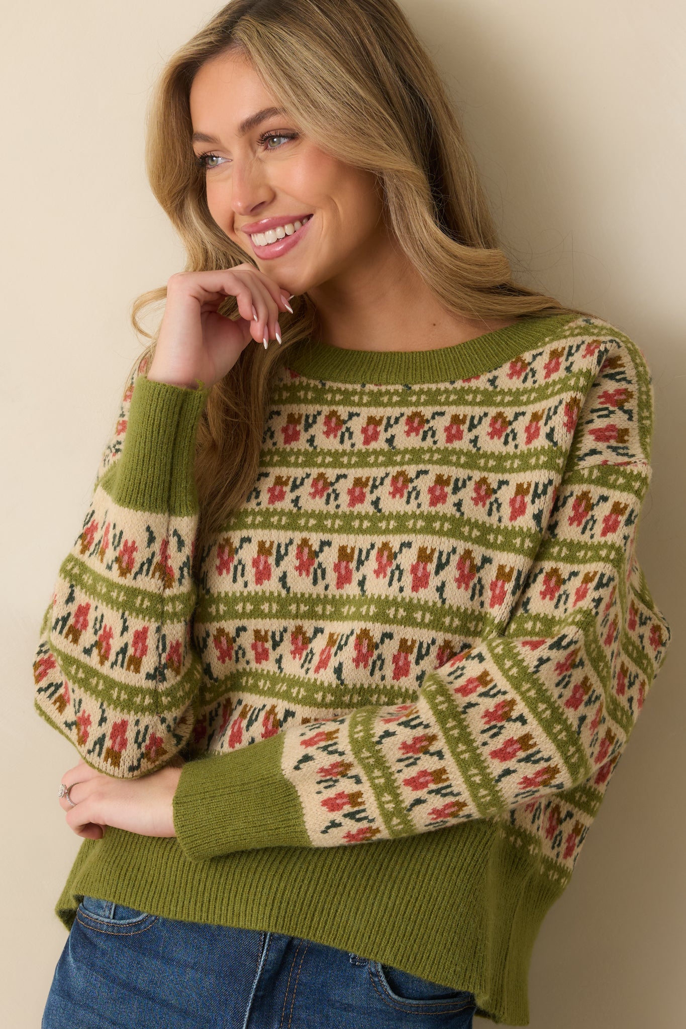 Sleeve and cuff of the olive sweater showing ribbed knit trim with patterned design above.