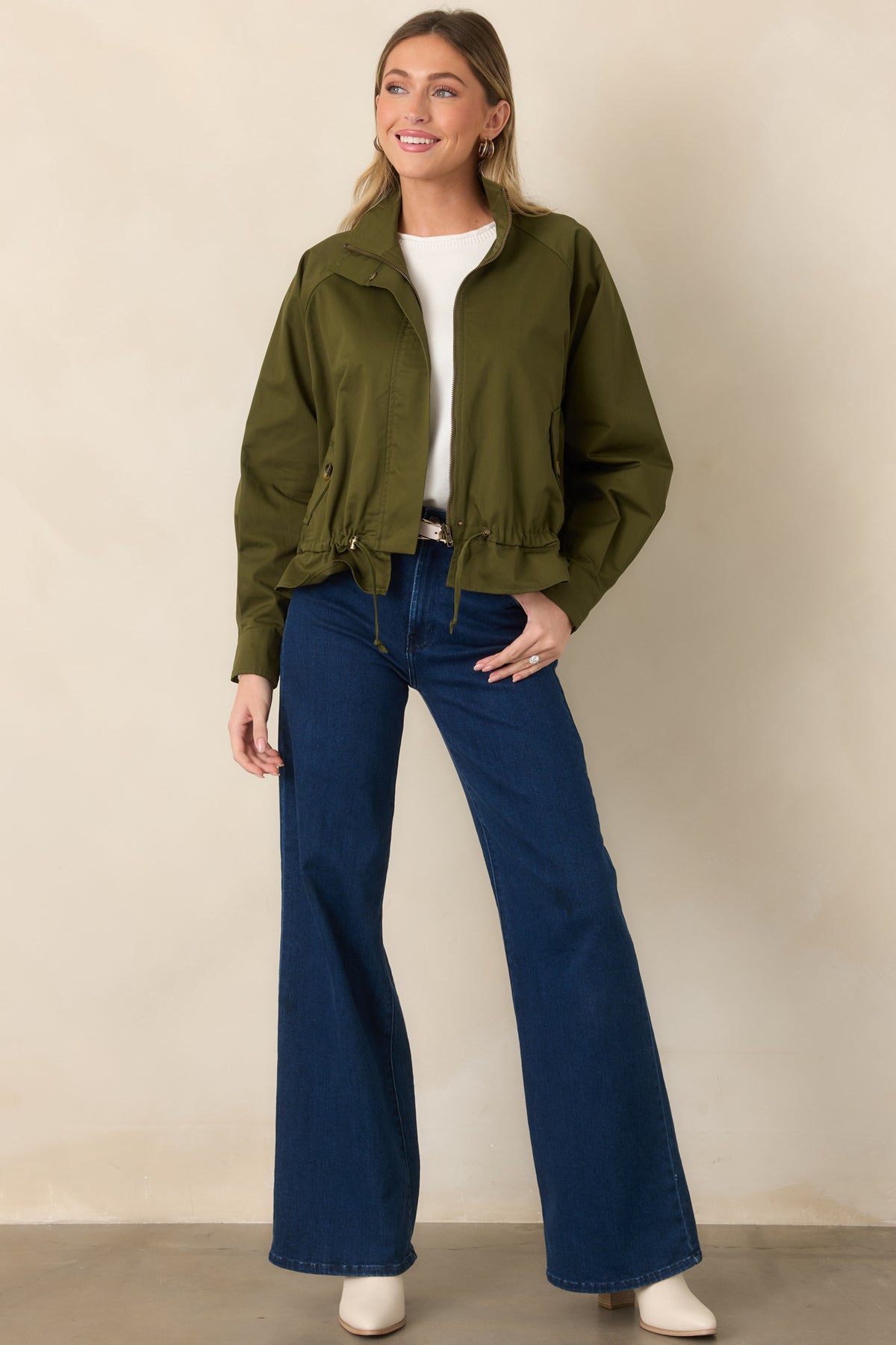 Olive utility-inspired jacket featuring snap accents, functional pockets, and a drawstring-defined silhouette.