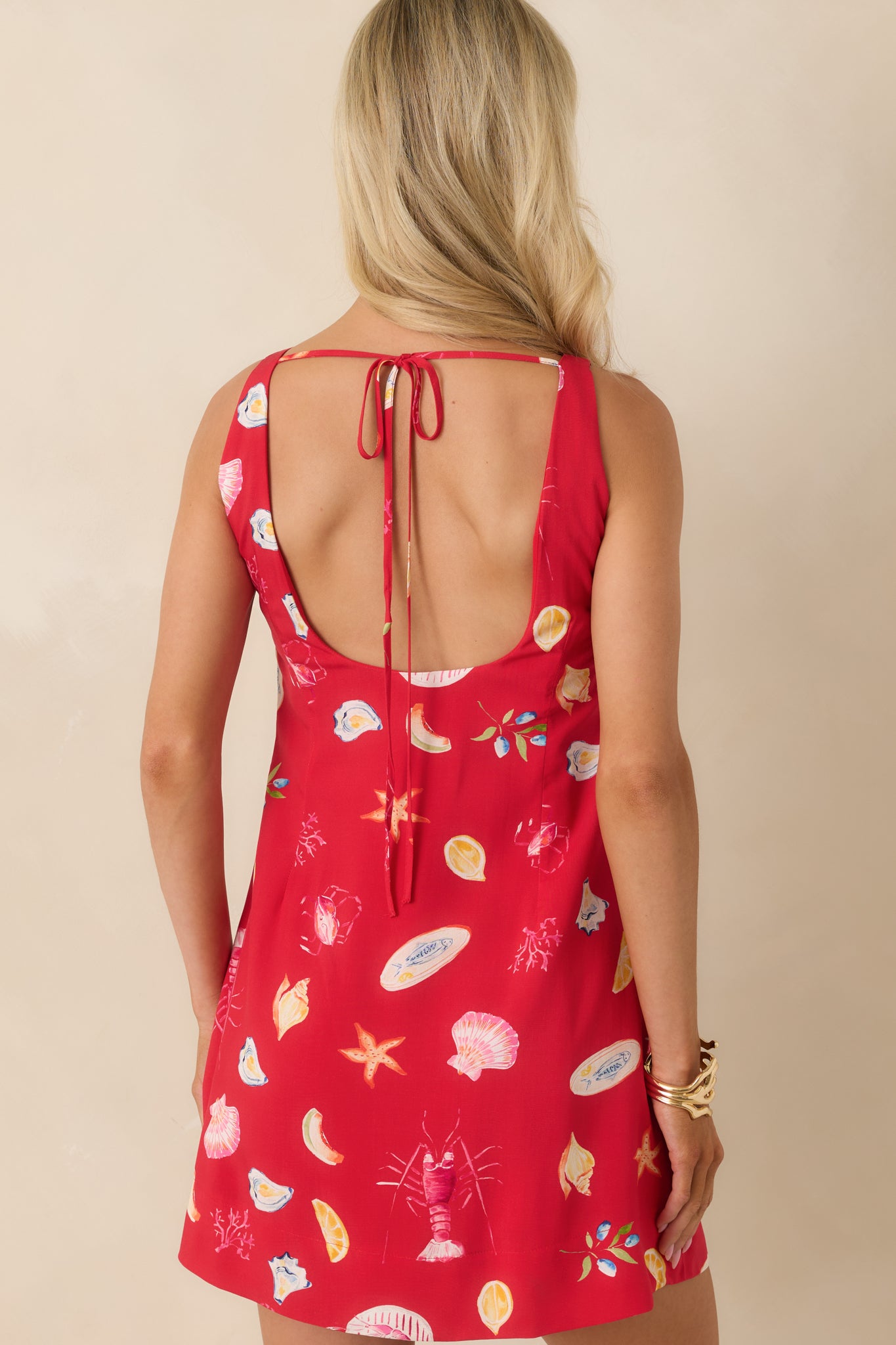 Back view of the mini dress featuring an open back design with adjustable tie closure.