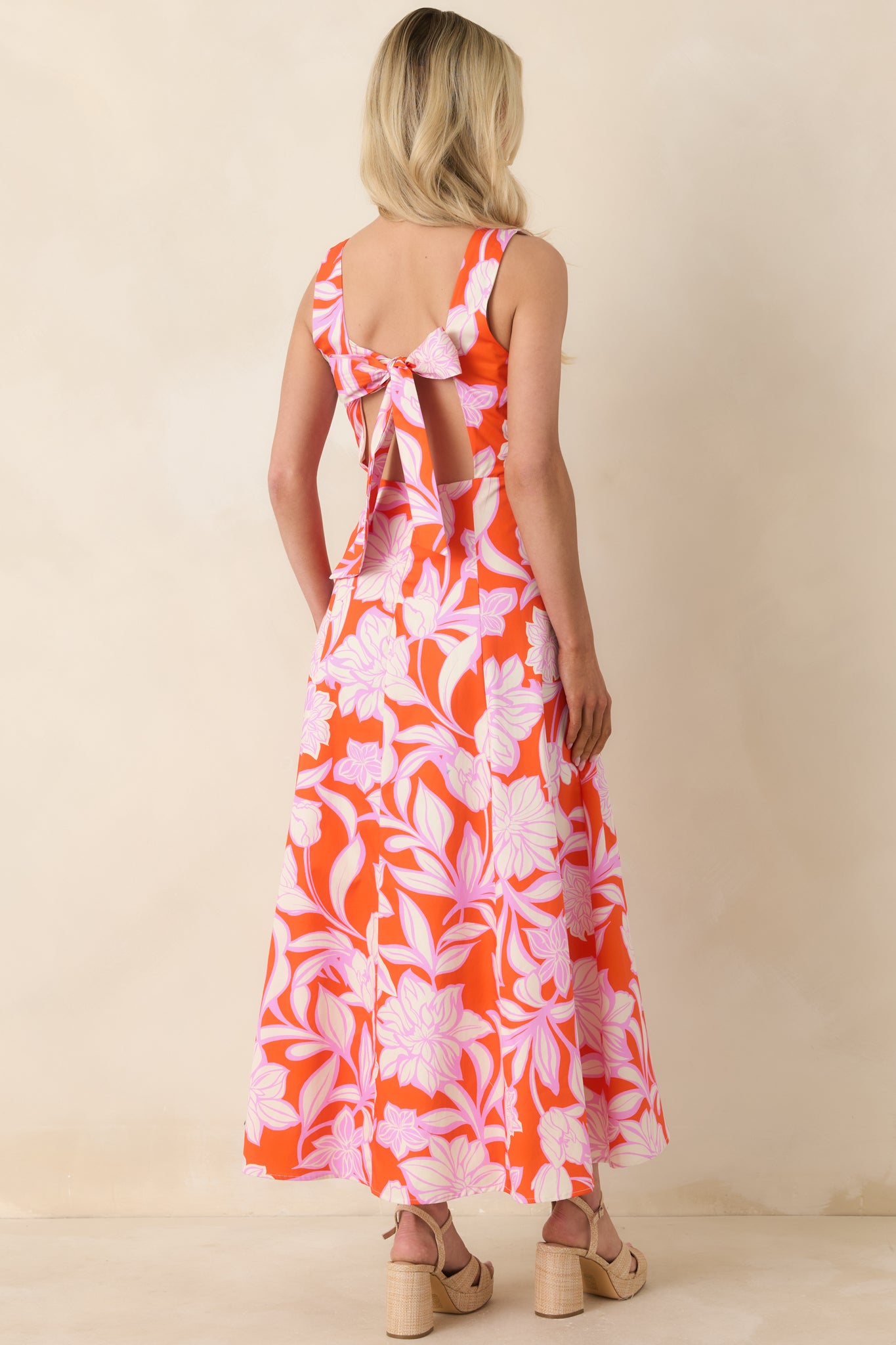 Orange floral maxi dress with open rear design and statement tie detail.