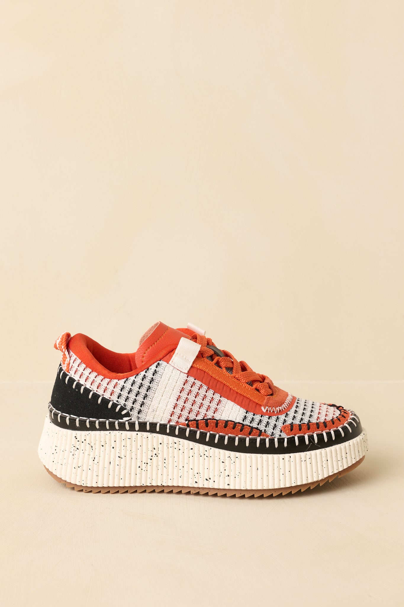 Close-up of the orange multicolor sneakers showing the whipstitch stitching, textured rubber outsole, and fabric detail.