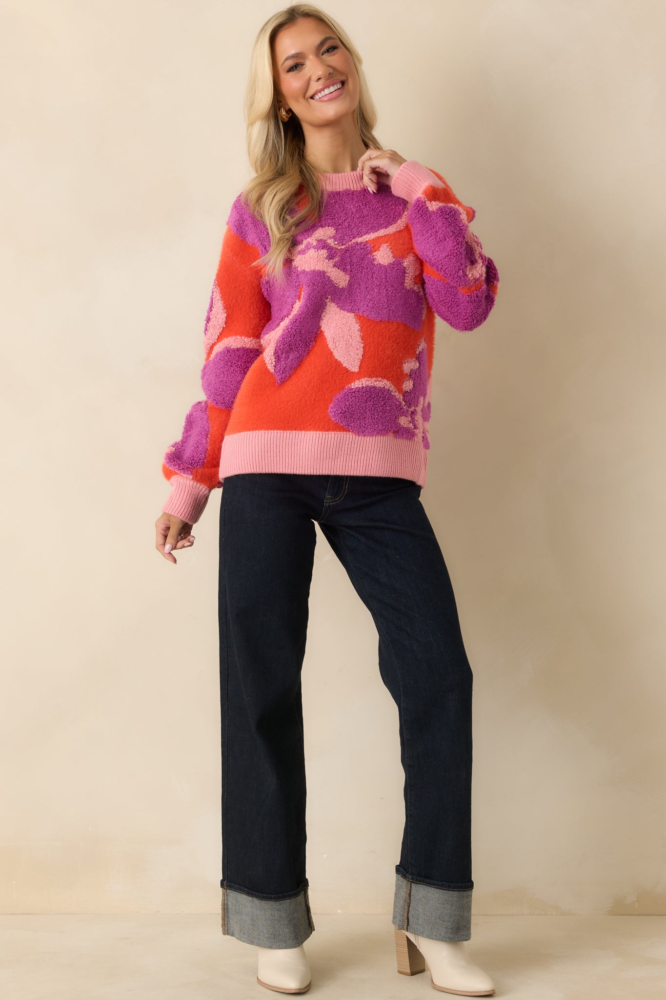 The orange sweater shows its bold floral pattern with a classic crew neckline and long sleeves.