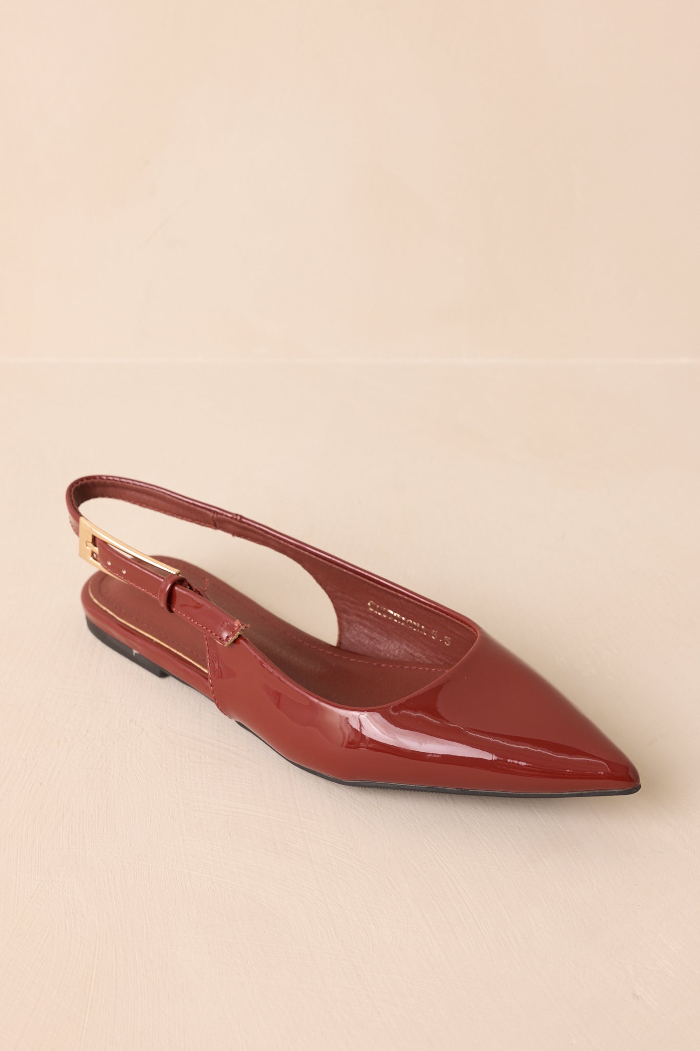 Overhead view of copper brown slingback flats with gold buckle strap detail.