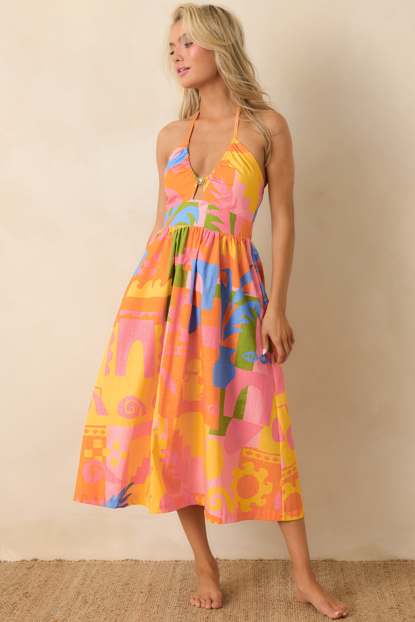 Orange multi abstract print midi dress with halter neckline and fitted bodice.