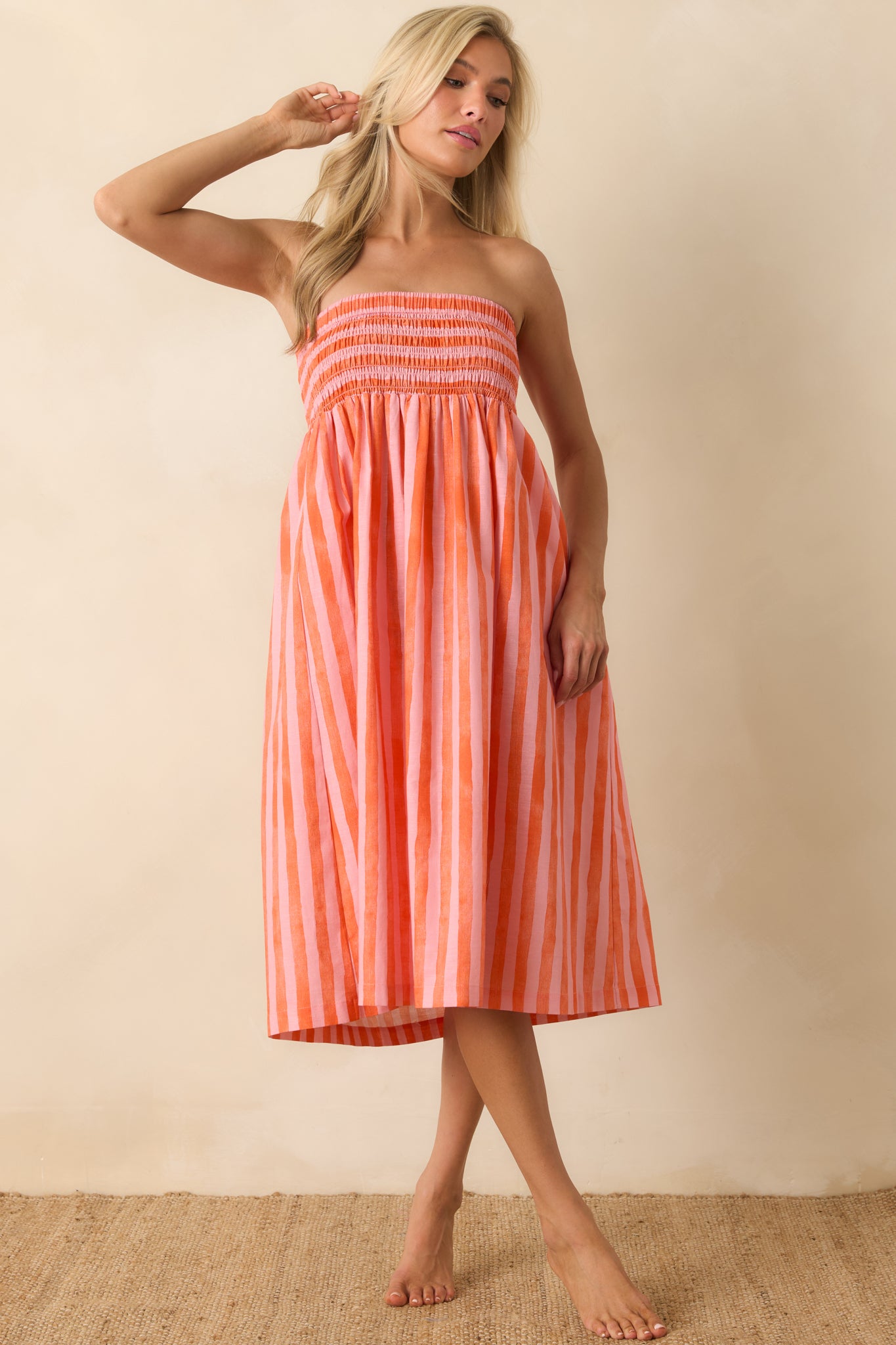 Pink and orange striped convertible midi dress featuring a strapless smocked bodice and lightweight linen-cotton blend fabric.