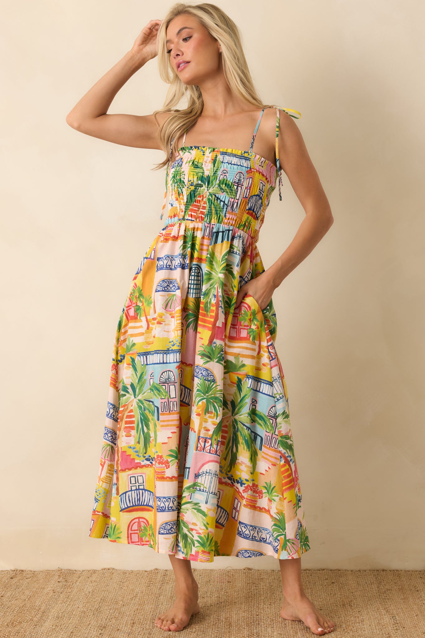 Multi-color coastal village print midi dress featuring a fully smocked bodice, adjustable shoulder tie straps, and a flowing midi-length skirt.