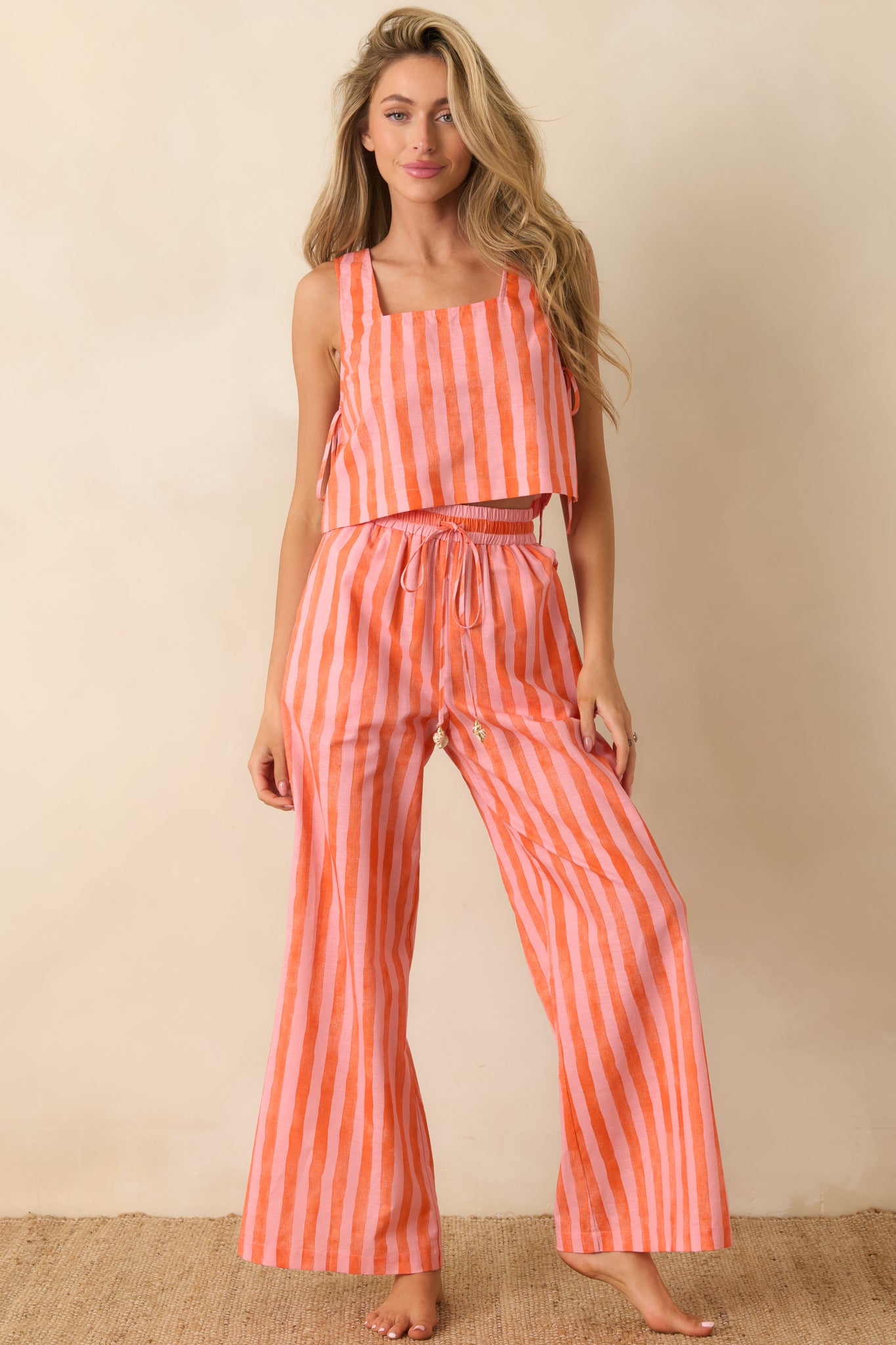 Pink and orange striped crop top featuring a square neckline, sleeveless silhouette, and relaxed cropped fit.