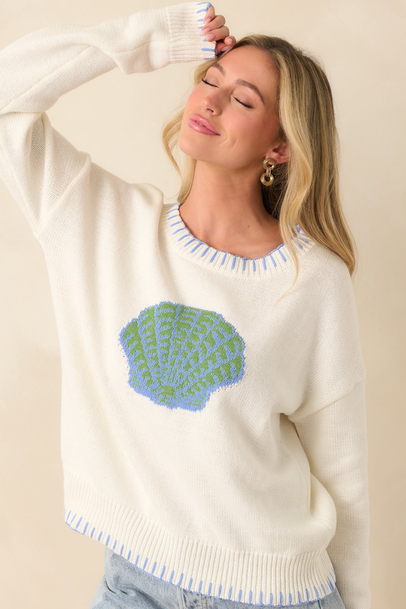 Close front view of white sweater highlighting soft fabric texture and textured shell graphic.