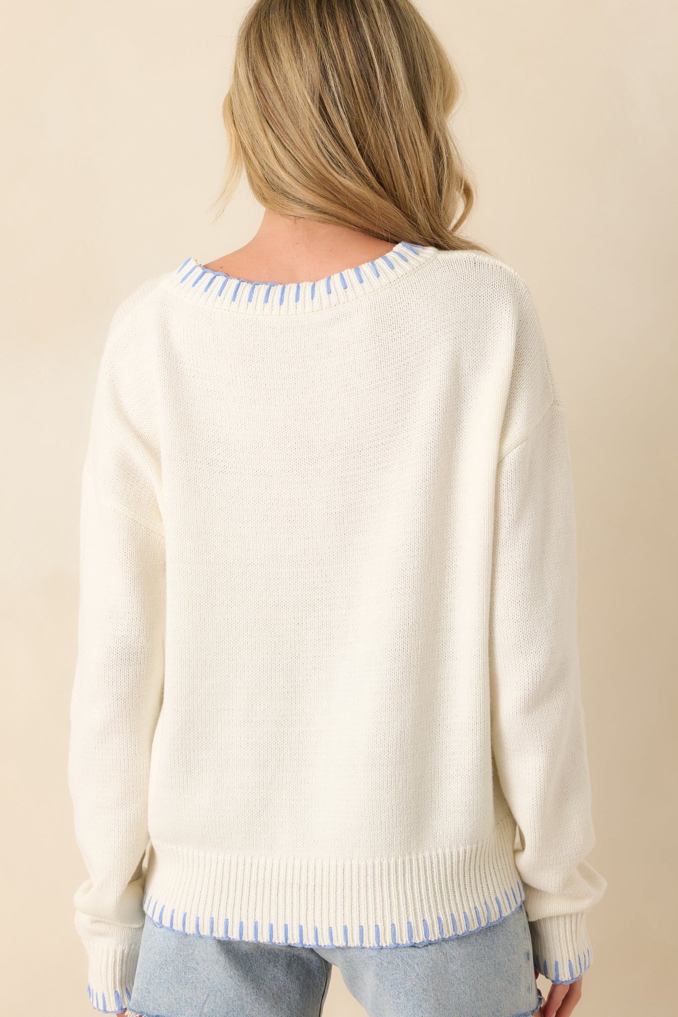 Back view of white knit sweater displaying relaxed fit, long sleeves, and smooth knit fabric.