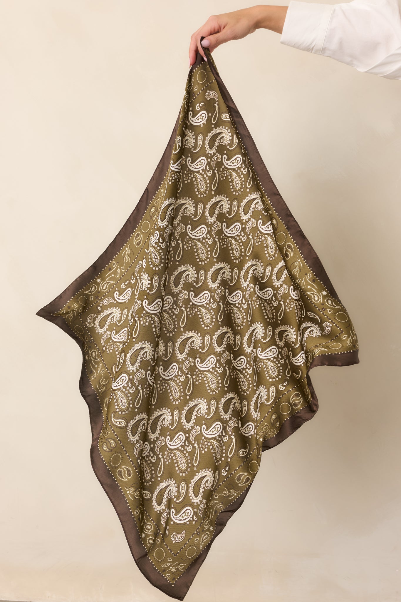 Detailed section of the paisley scarf highlighting the smooth satin texture and contrasting border around the printed fabric.