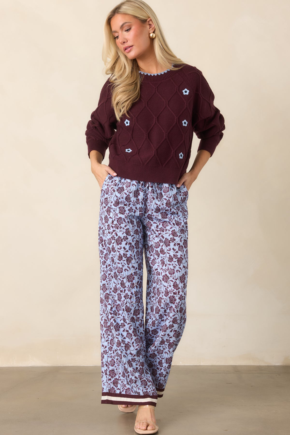 Pale lilac wide-leg pants covered in burgundy florals with contrasting burgundy and ivory striped hems.