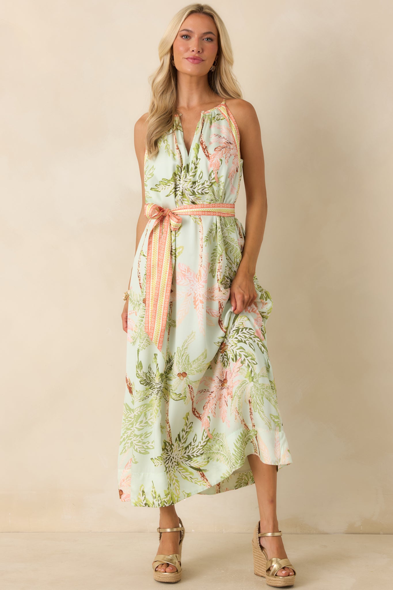 Palm print maxi dress with a sweeping skirt, soft gathered neckline, and a tropical watercolor-inspired pattern in muted resort tones.