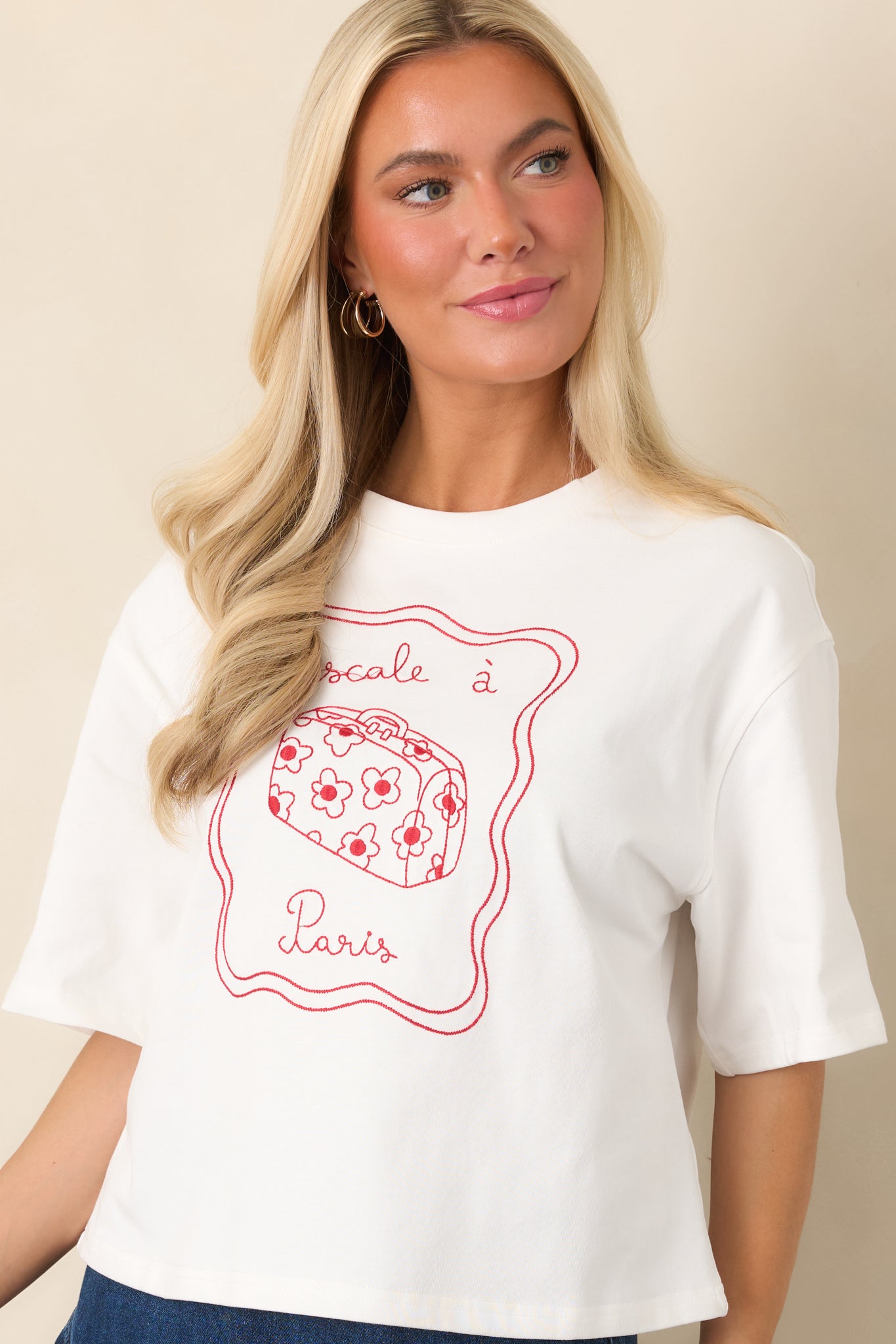 Upper front portion of the top showcasing the classic crew neckline, short sleeves, and red embroidered Paris-inspired artwork.