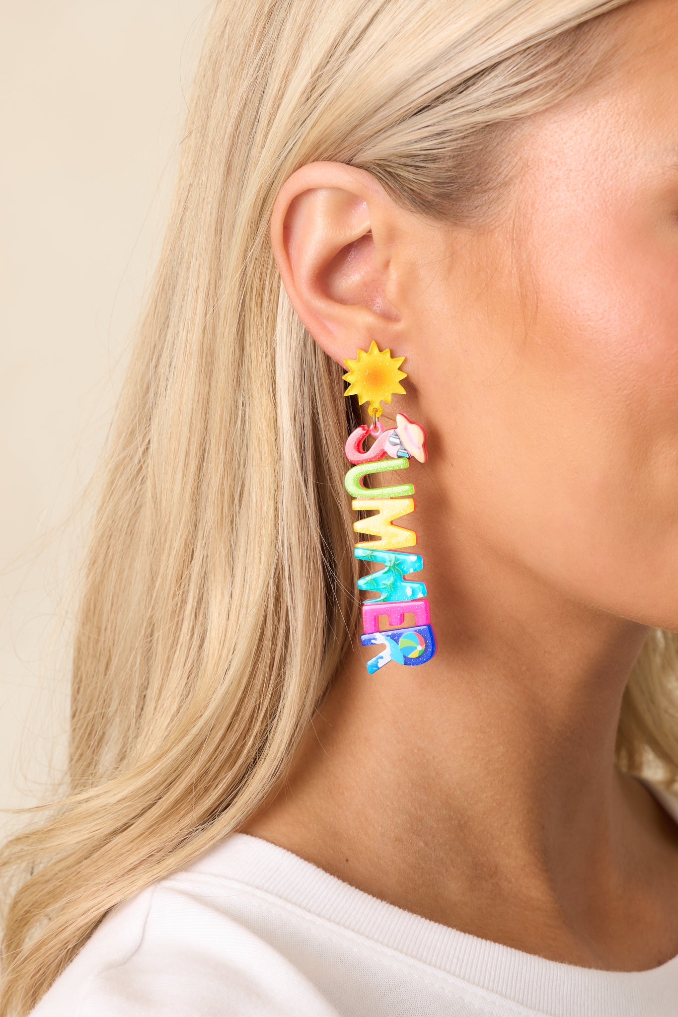 A partial view of the multi-color acrylic earrings, highlighting the yellow and orange spiky acrylic stud and gold hardware.
