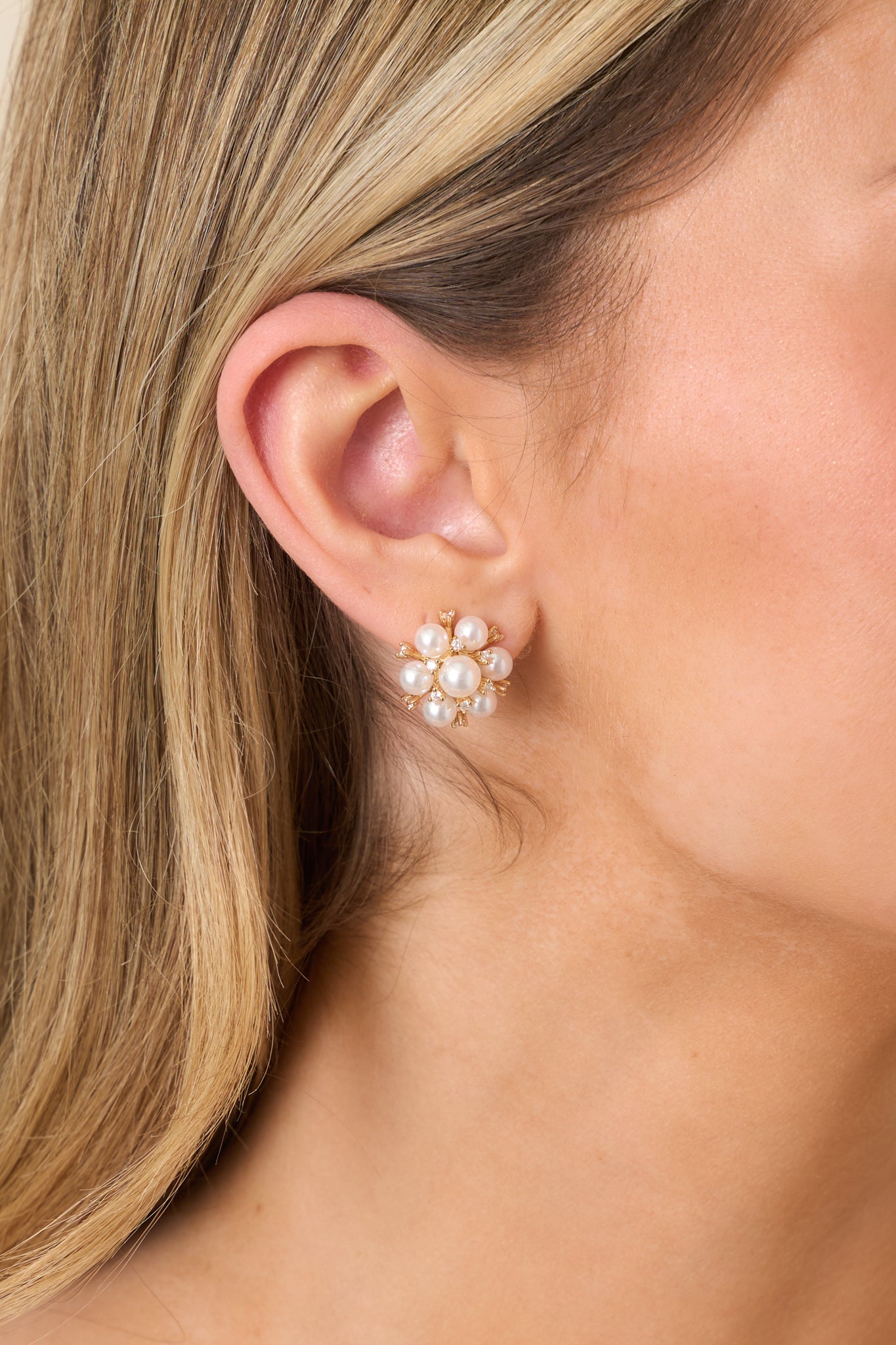 Close-up of pearl cluster stud earrings showing floral arrangement of pearls, subtle crystal details, and polished gold setting.