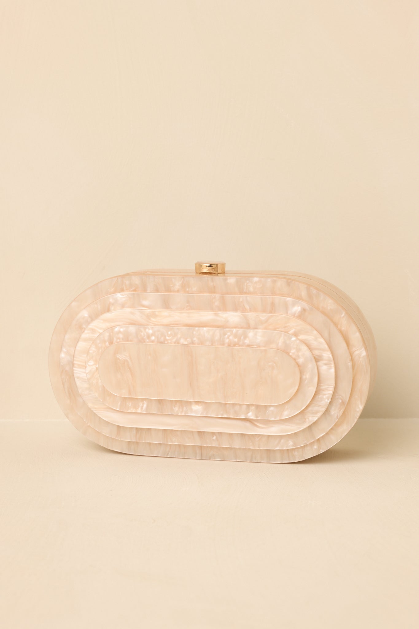 Elegant oval clutch showcasing a smooth pearlescent surface, removable chain strap, and polished evening design.