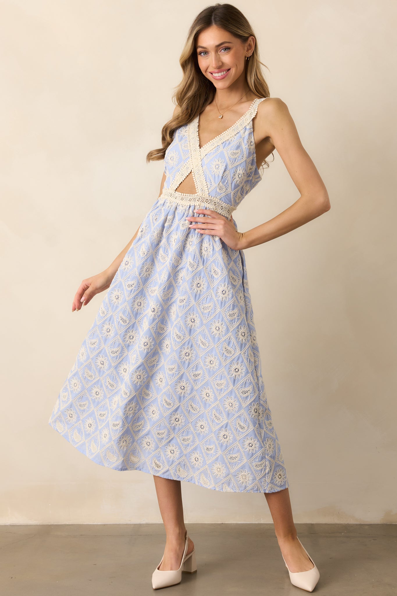 A charming periwinkle dress with lace embroidery throughout, a chic v-neckline, and a cutout in the bodice, offering adjustable straps for a perfect, personalized fit.