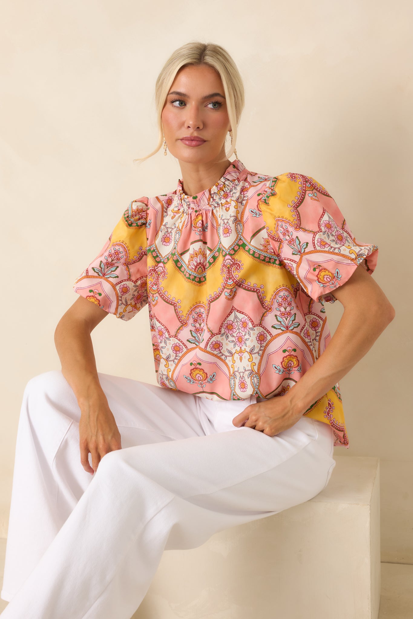 Pink and marigold print top in 100% cotton featuring a colorful vintage-inspired ornamental scarf print, ruffled mock neckline, and short bubble sleeves.
