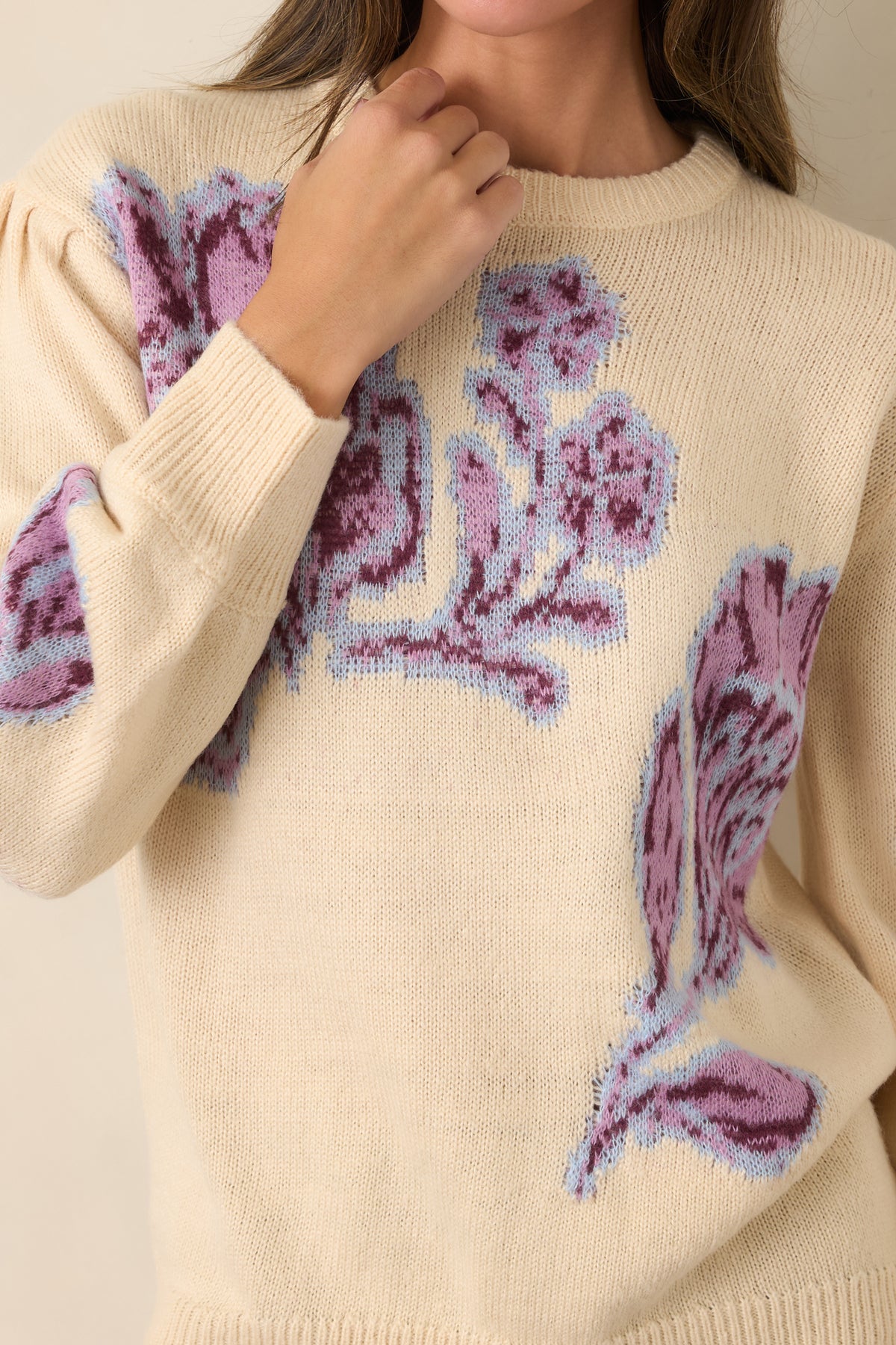 Close-up highlights the oversized pink and burgundy blooms, pale blue outlines, and soft texture of the vanilla knit.