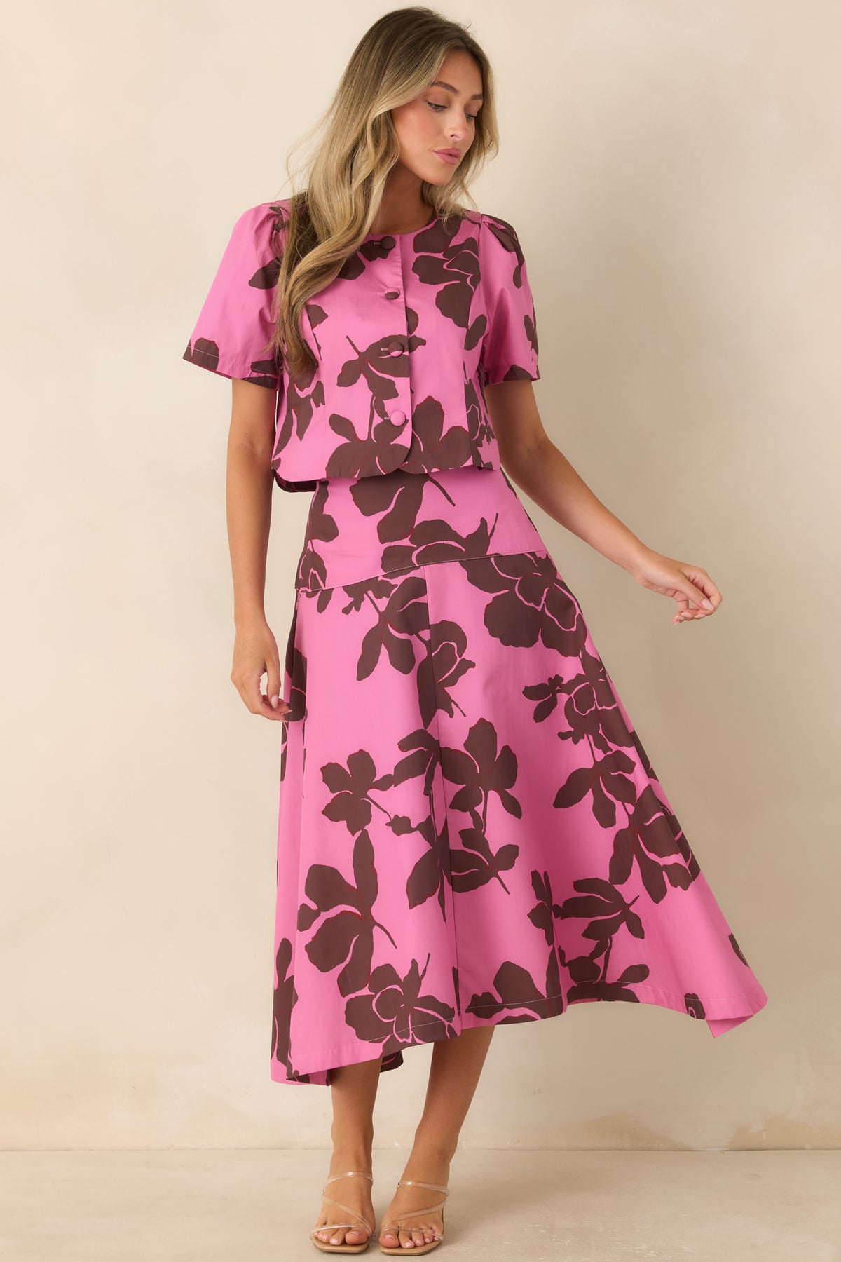 Pink cotton midi skirt featuring an oversized chocolate brown floral print, wide fitted waistband, and full A-line silhouette.
