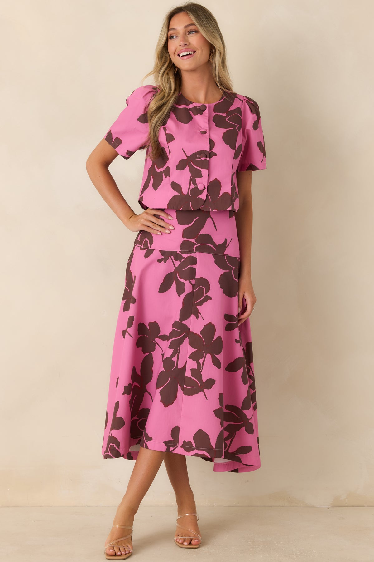 Floral midi skirt showcasing a bright pink base, bold chocolate brown blooms, structured waistband, and flowing full A-line shape.