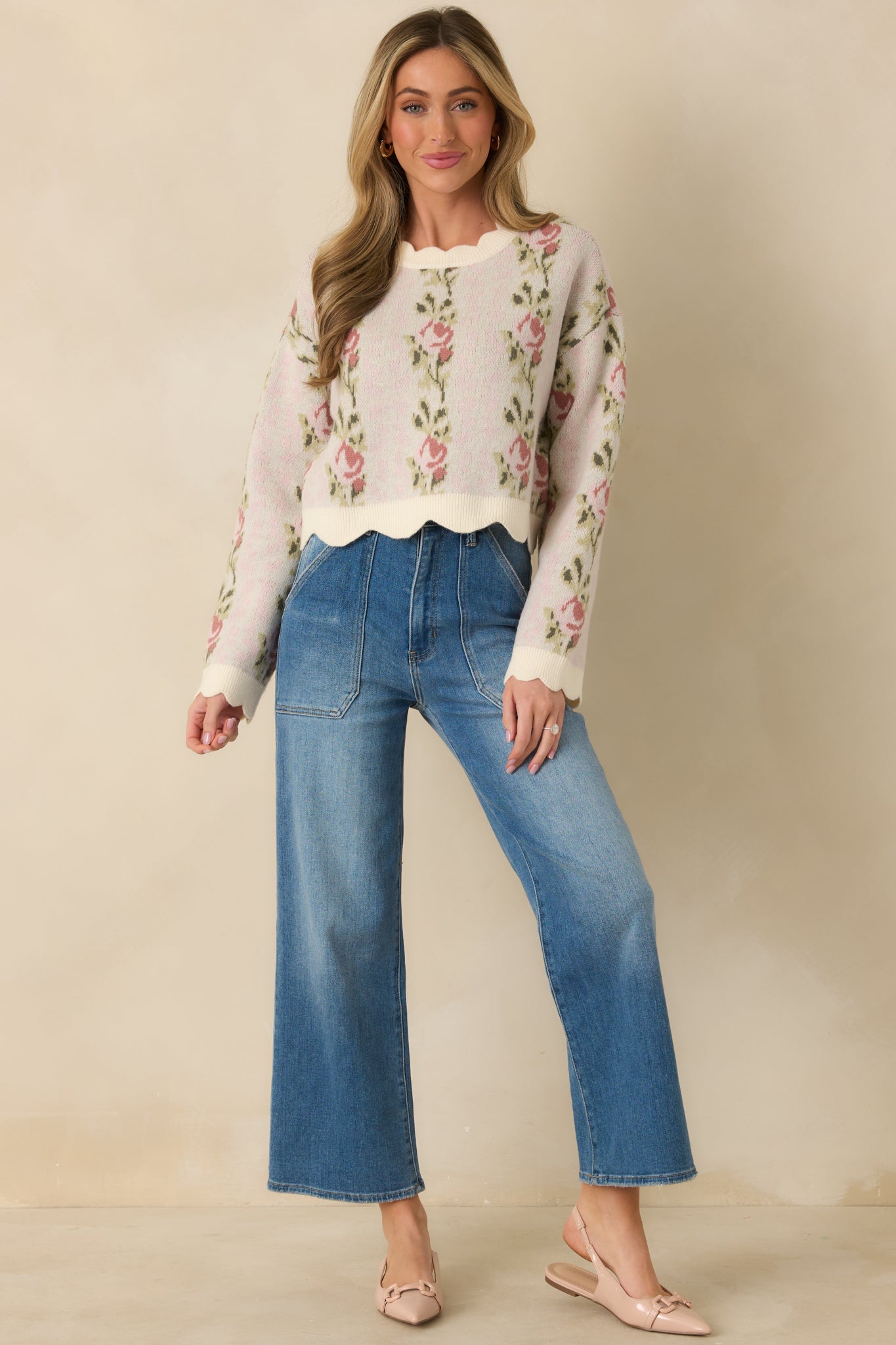 Pink floral knit sweater with a round neckline, long sleeves, and scalloped hem detailing.