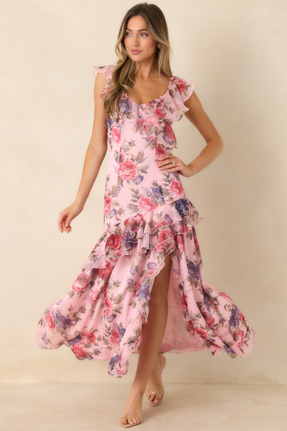 Pink floral maxi dress with ruffled trim sweeping diagonally across the skirt and around the high slit.