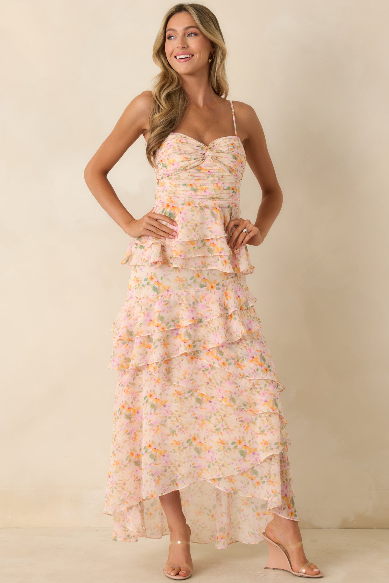 Pink floral maxi dress with adjustable straps, asymmetrical hem ruffles, and an elegant flowing fit.