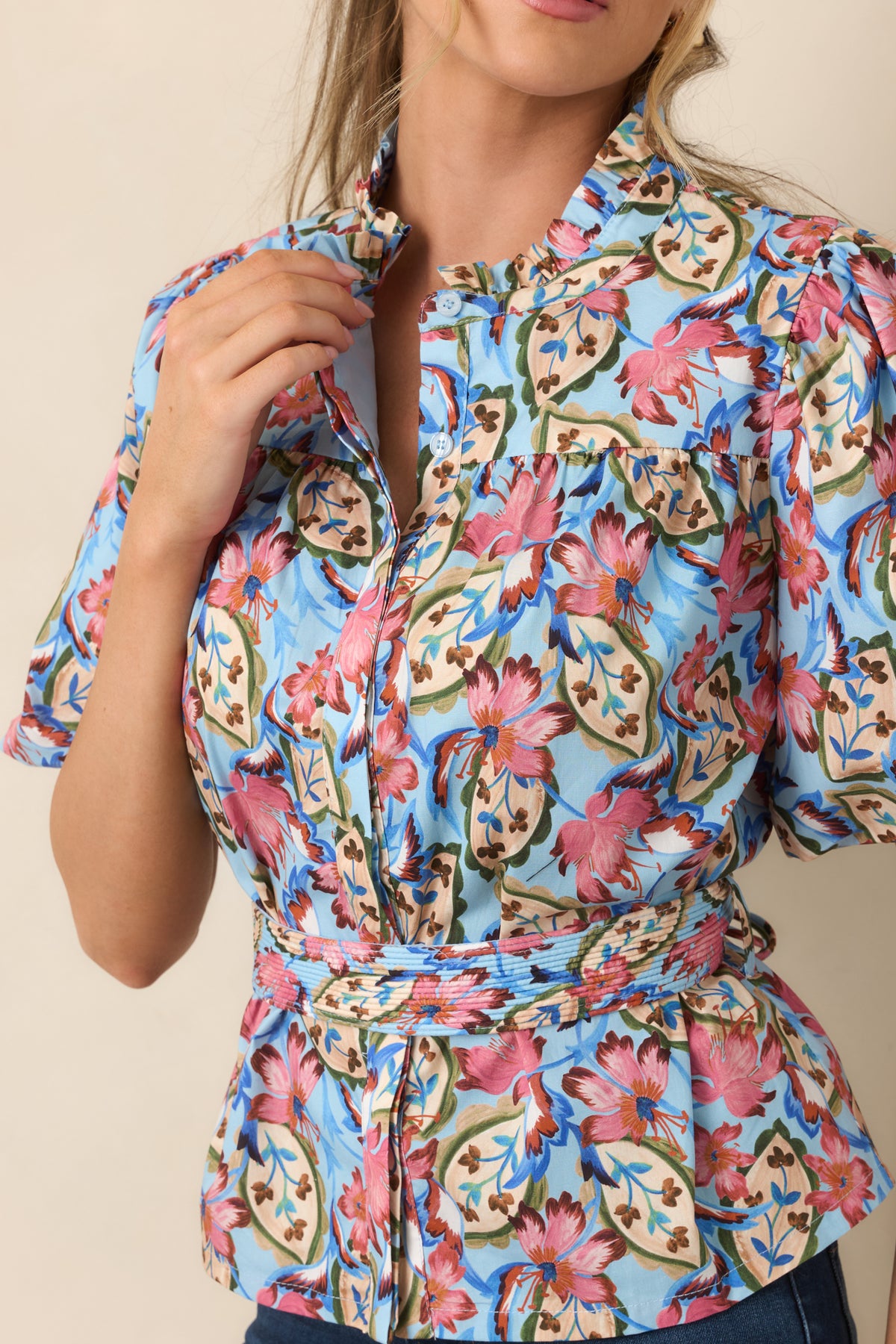 Close-up of the pink floral print, ruffled stand collar, button-front closure, and gathered shoulder detailing.