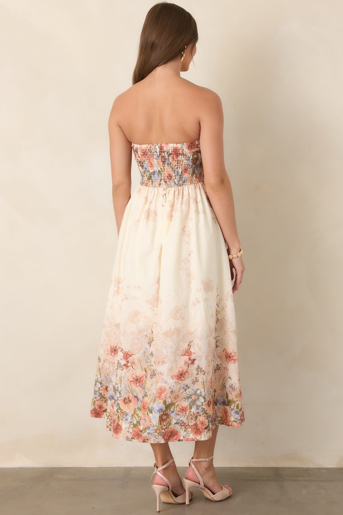 Rear view of the pink floral cotton midi dress showcasing its smocked back panel, concealed zipper, elasticized waistband, and flowing skirt.